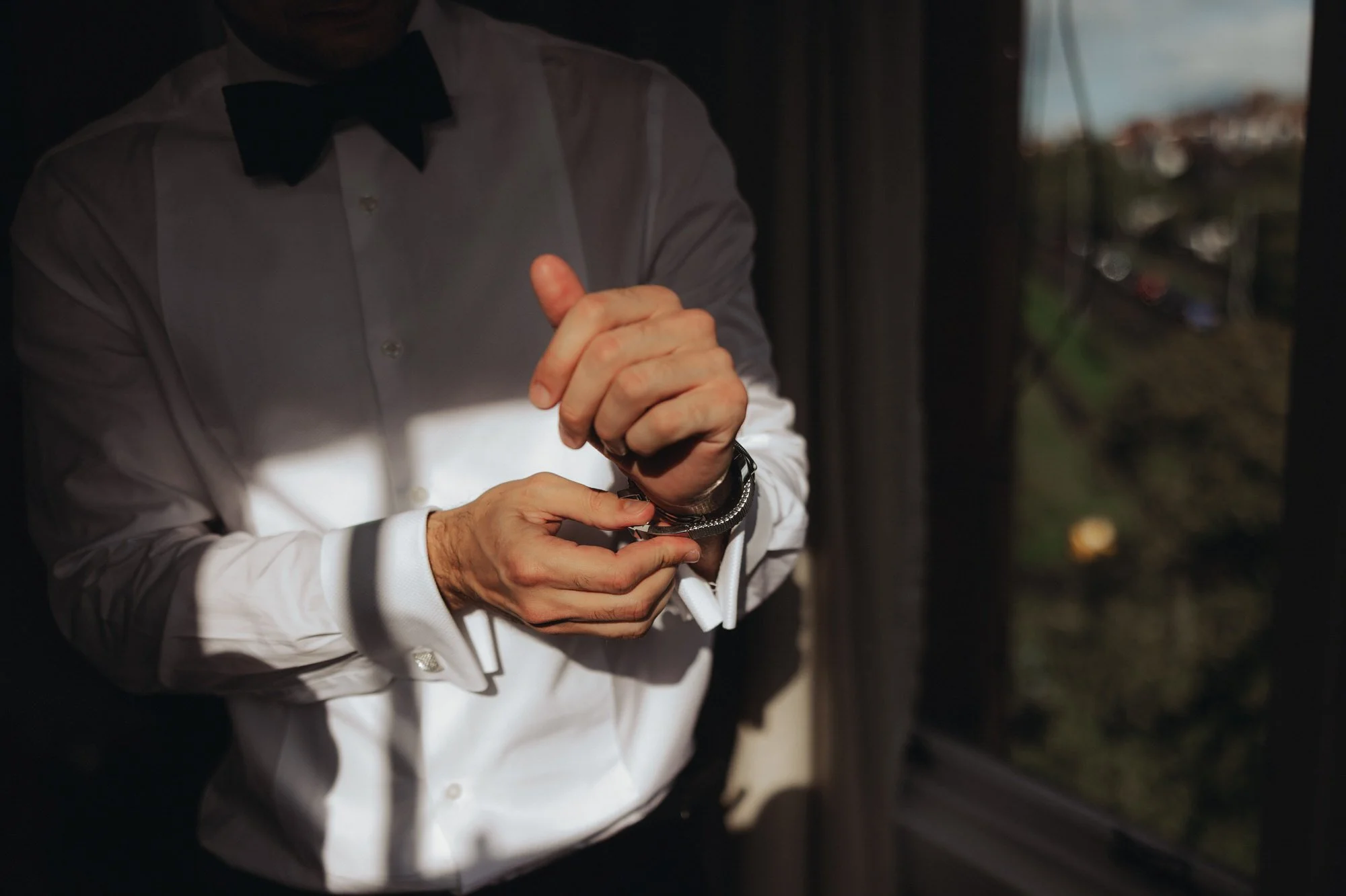Close-up of the groom fastening his cufflinks