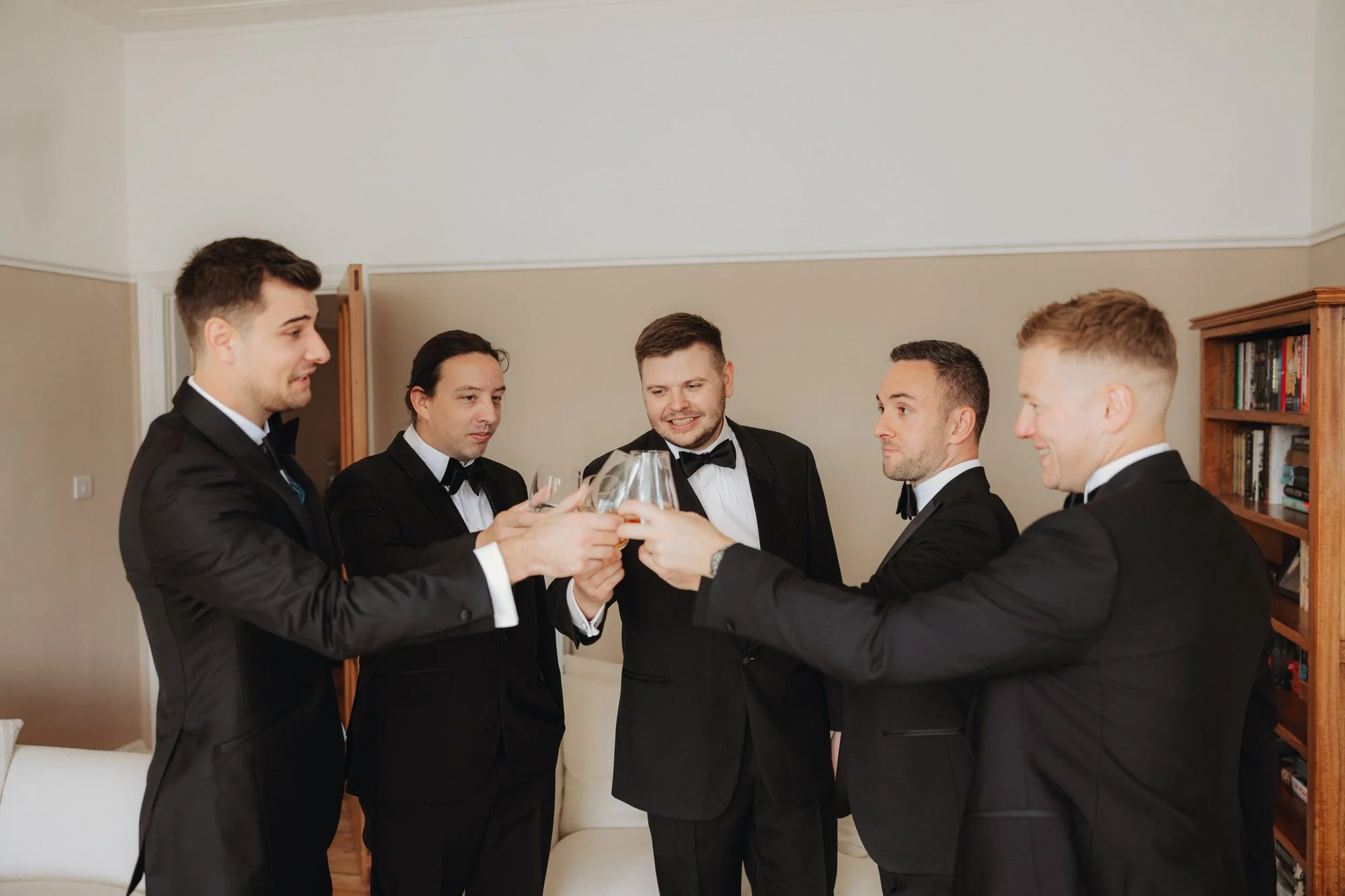 The groom and groomsmen raising glasses together