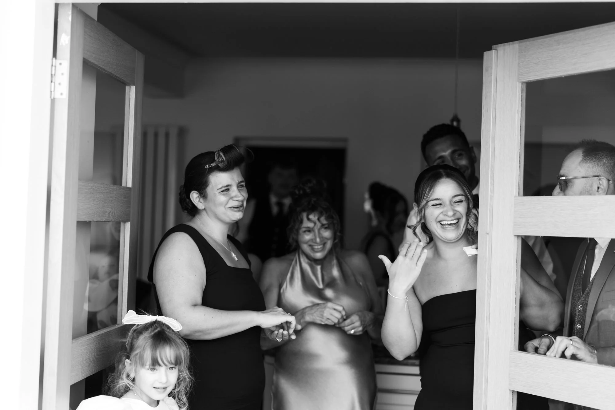 Family and bridesmaids laughing in the doorway
