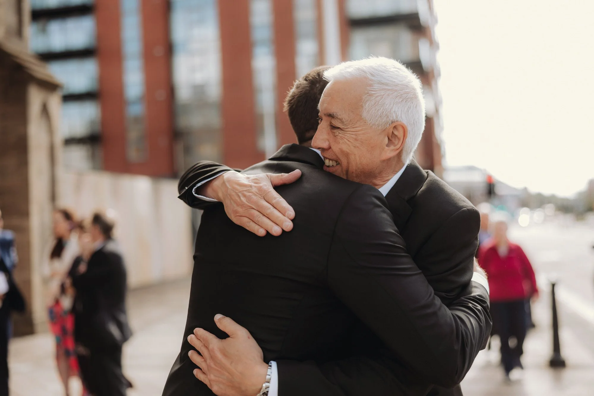 Two wedding guests greeting each other with a hug