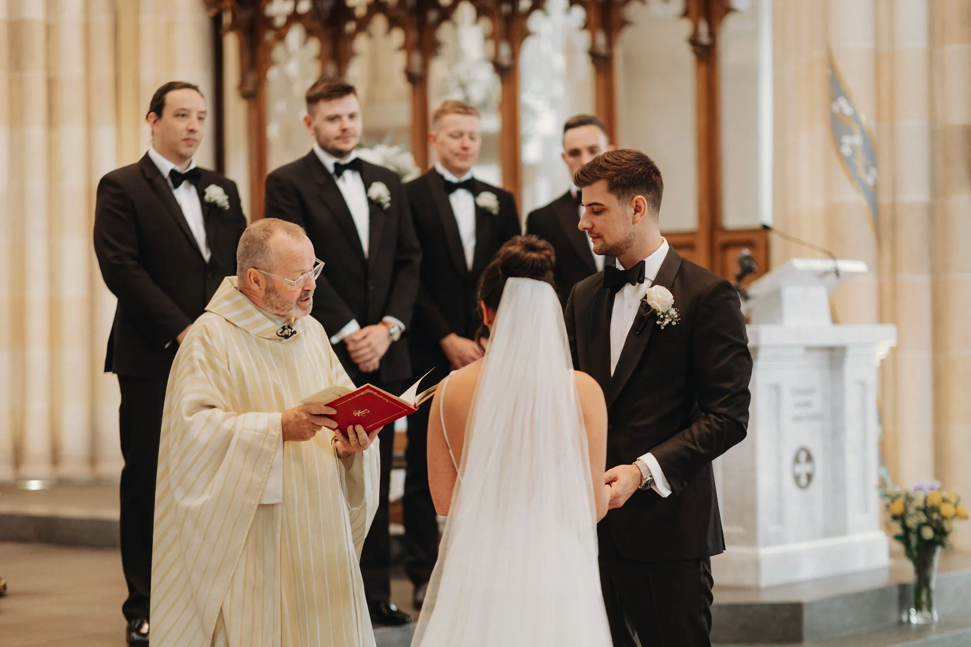 Caterina and Jonathan standing with the priest during their vows