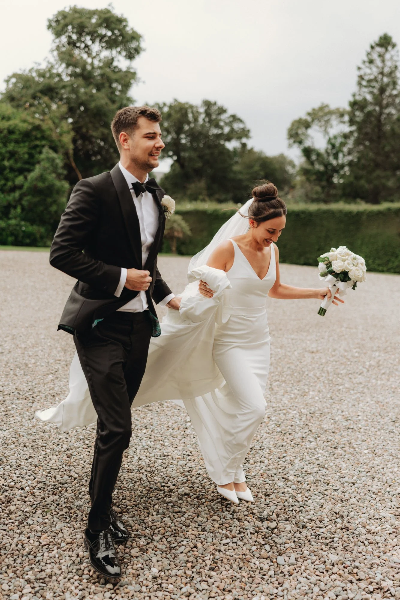 The newlyweds laughing beside their wedding car
