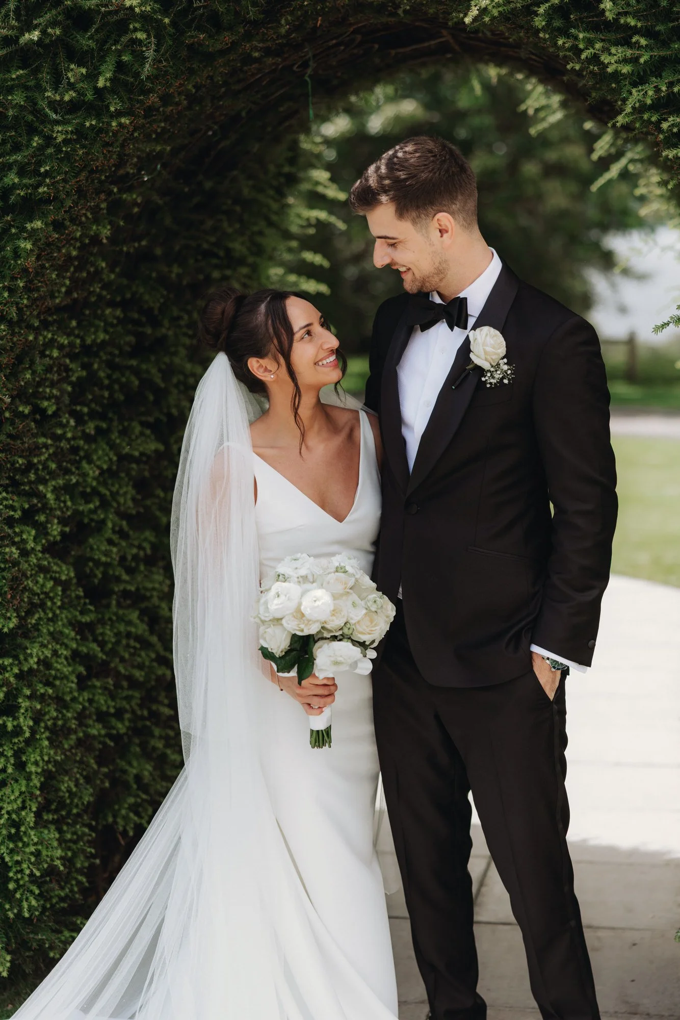 The newlyweds laughing beside the garden hedge