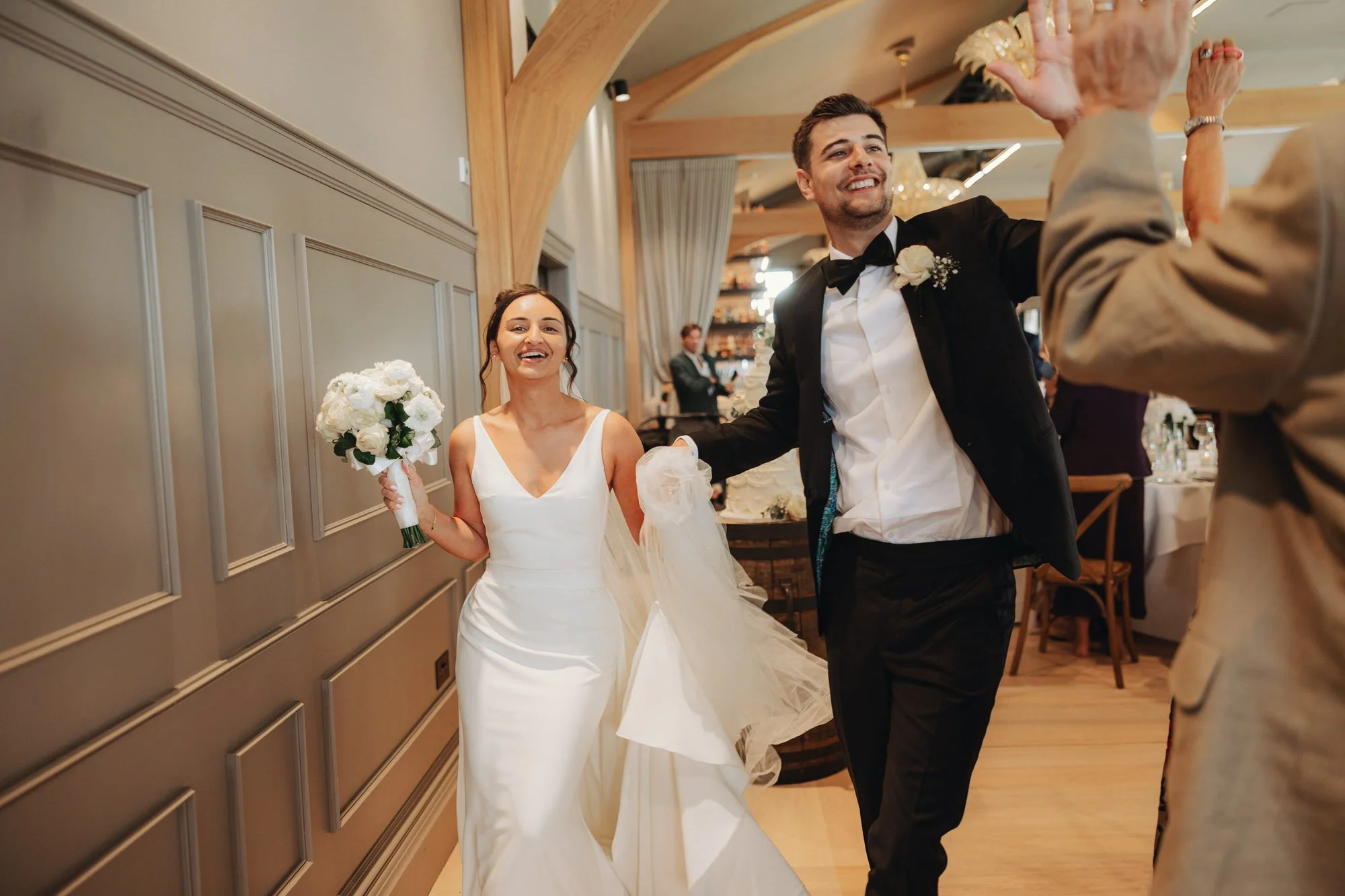 Caterina and Jonathan entering the reception with raised glasses