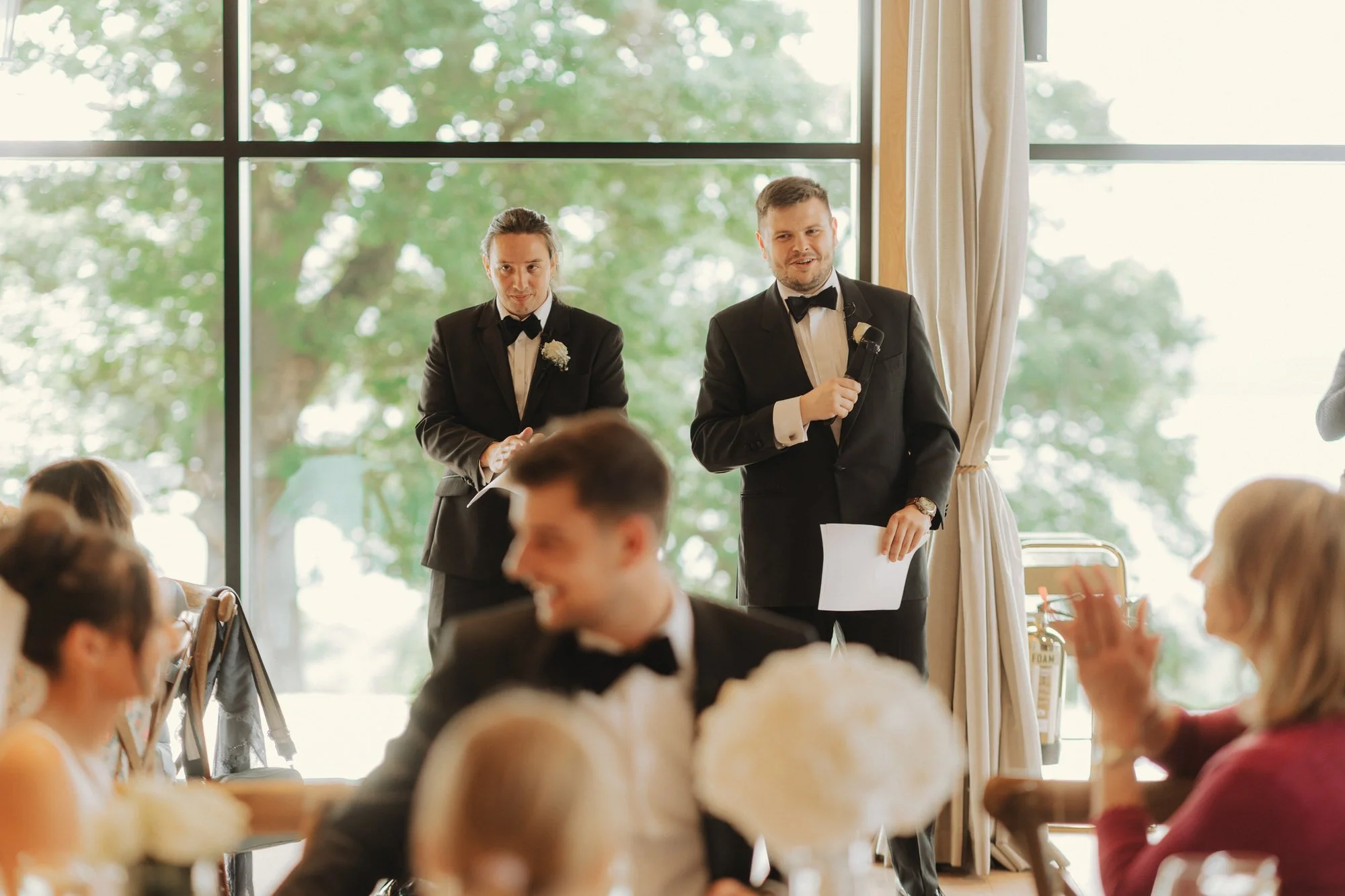 Jonathan and a speaker standing during the wedding speeches