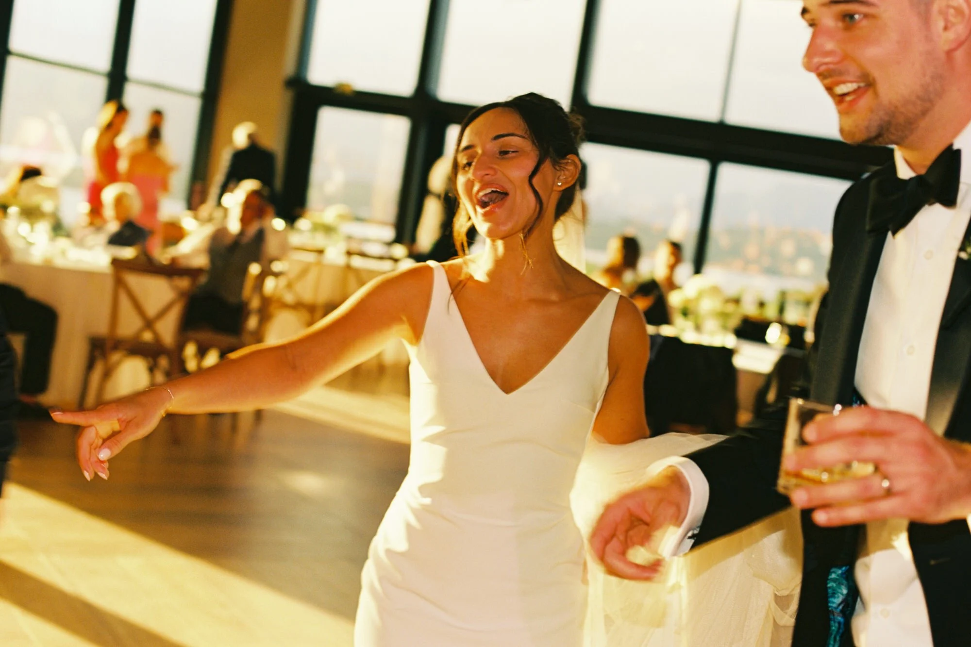 The couple holding drinks inside the sunlit pavilion