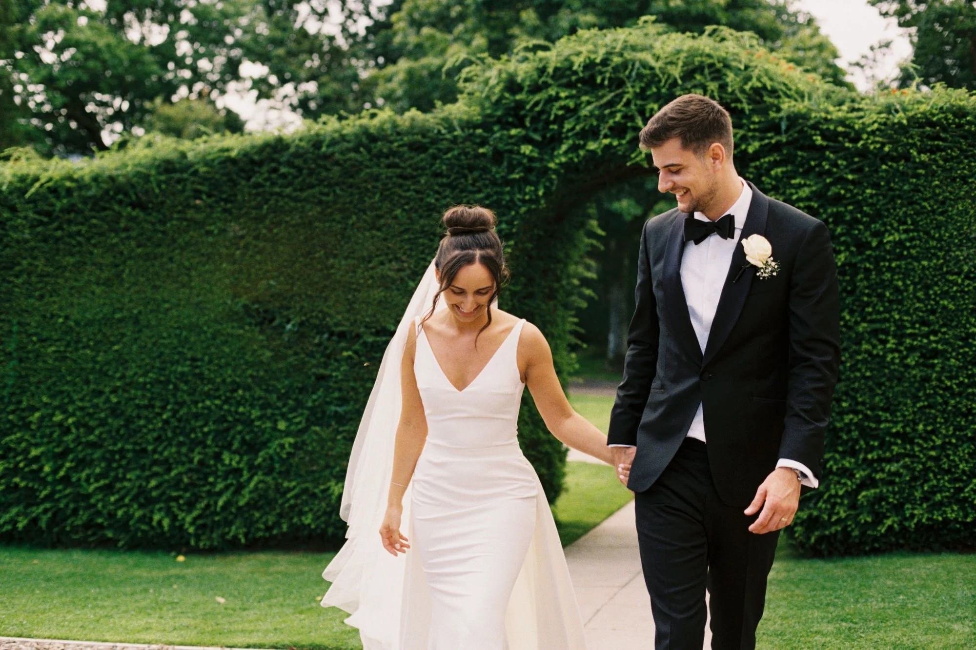 The newlyweds holding hands on a garden path