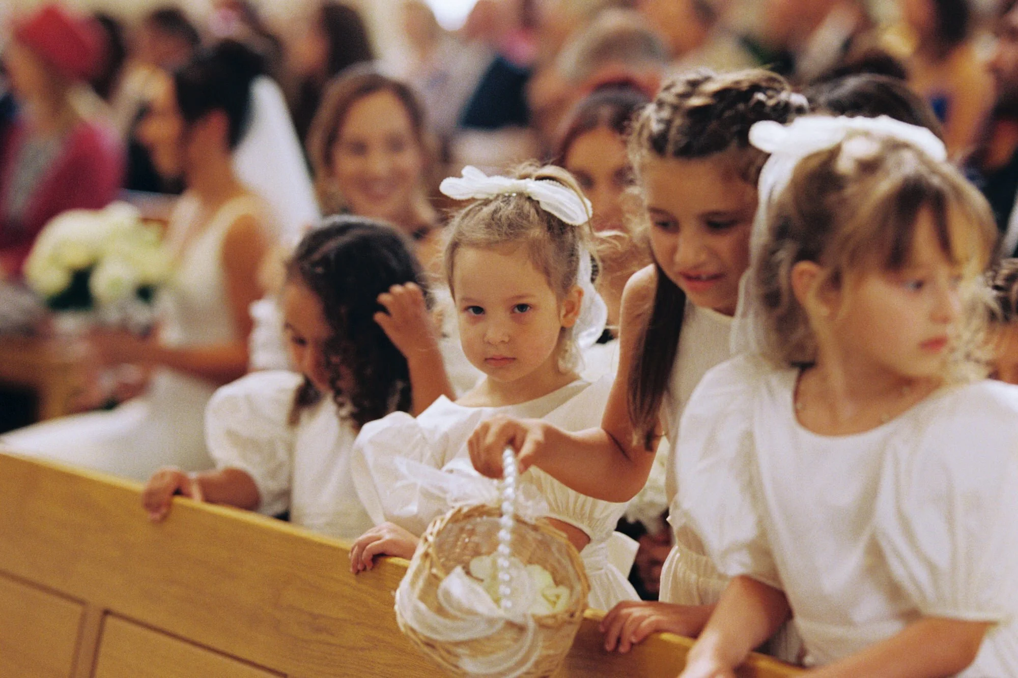 Flower girls watching the ceremony from the front pew