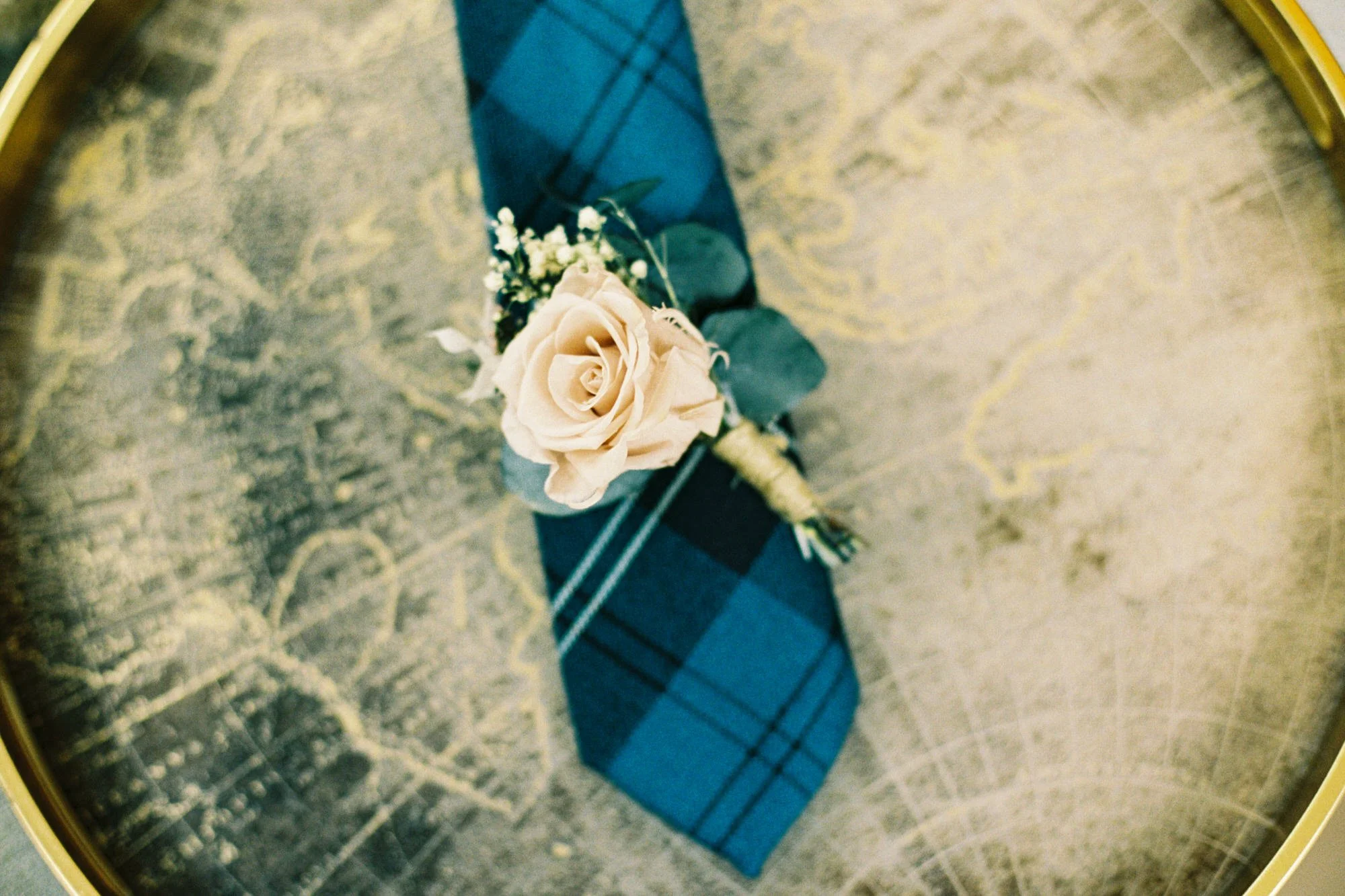 Blue tartan tie and cream buttonhole on a glass table