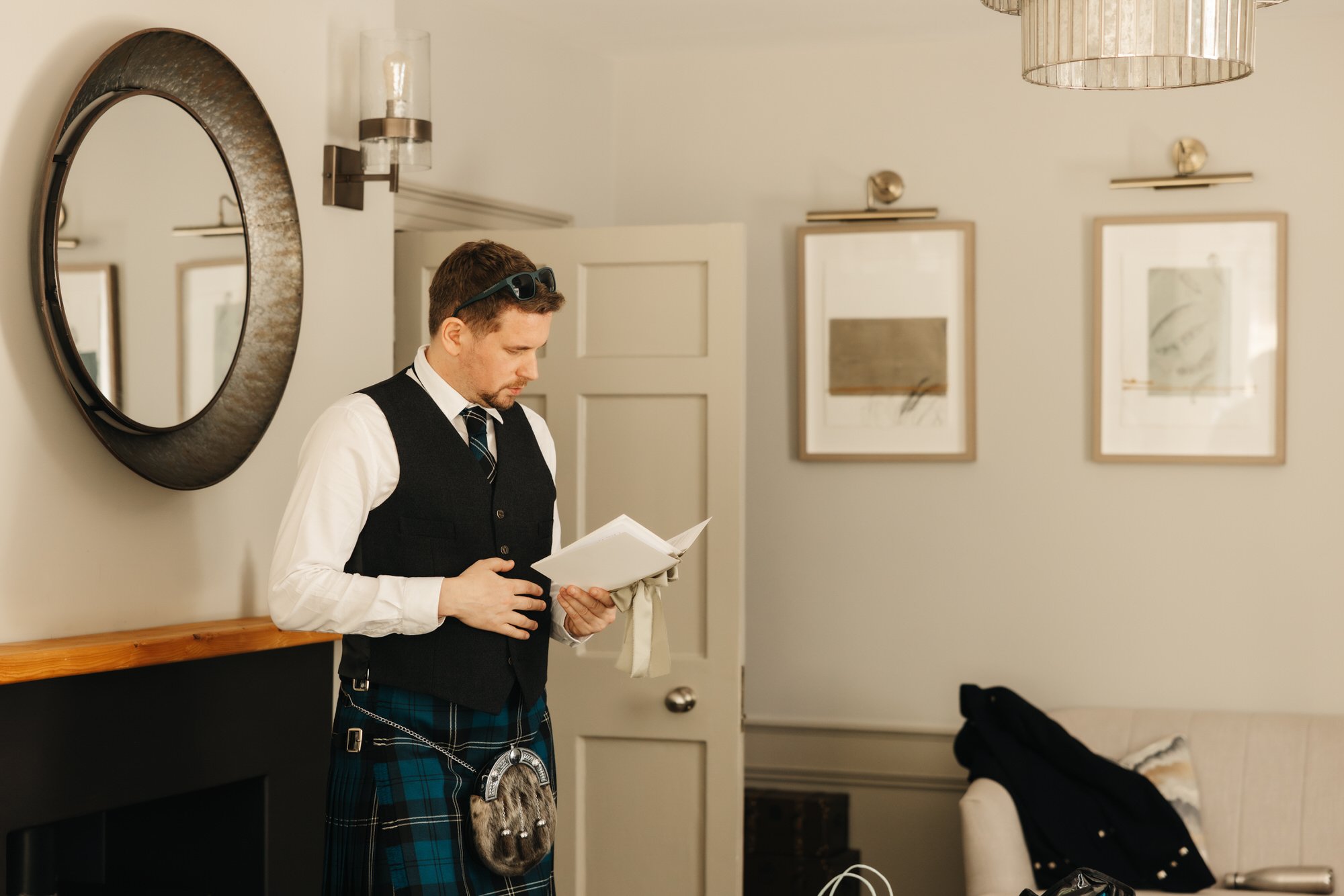 Groom reading a card in a bright room at Pratis House