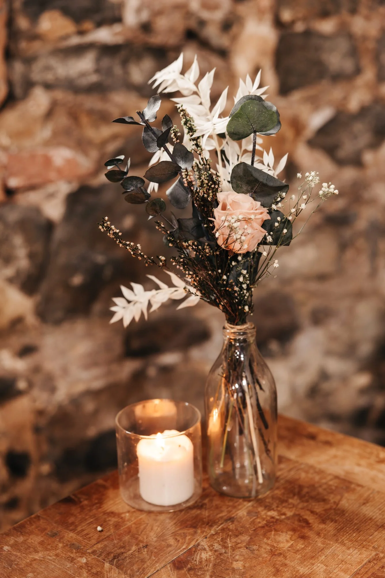 Dried flowers and a candle beside the stone ceremony wall