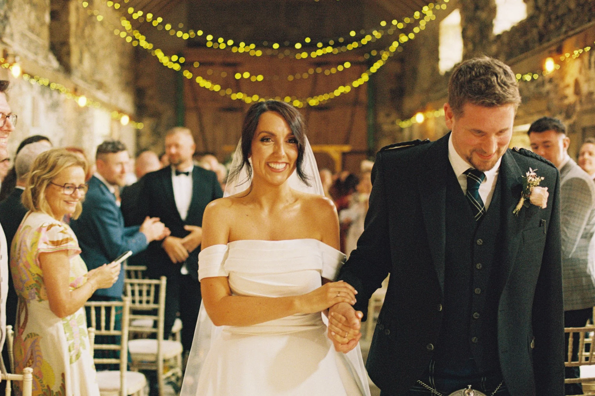 Claire and Alex walking back through their wedding guests