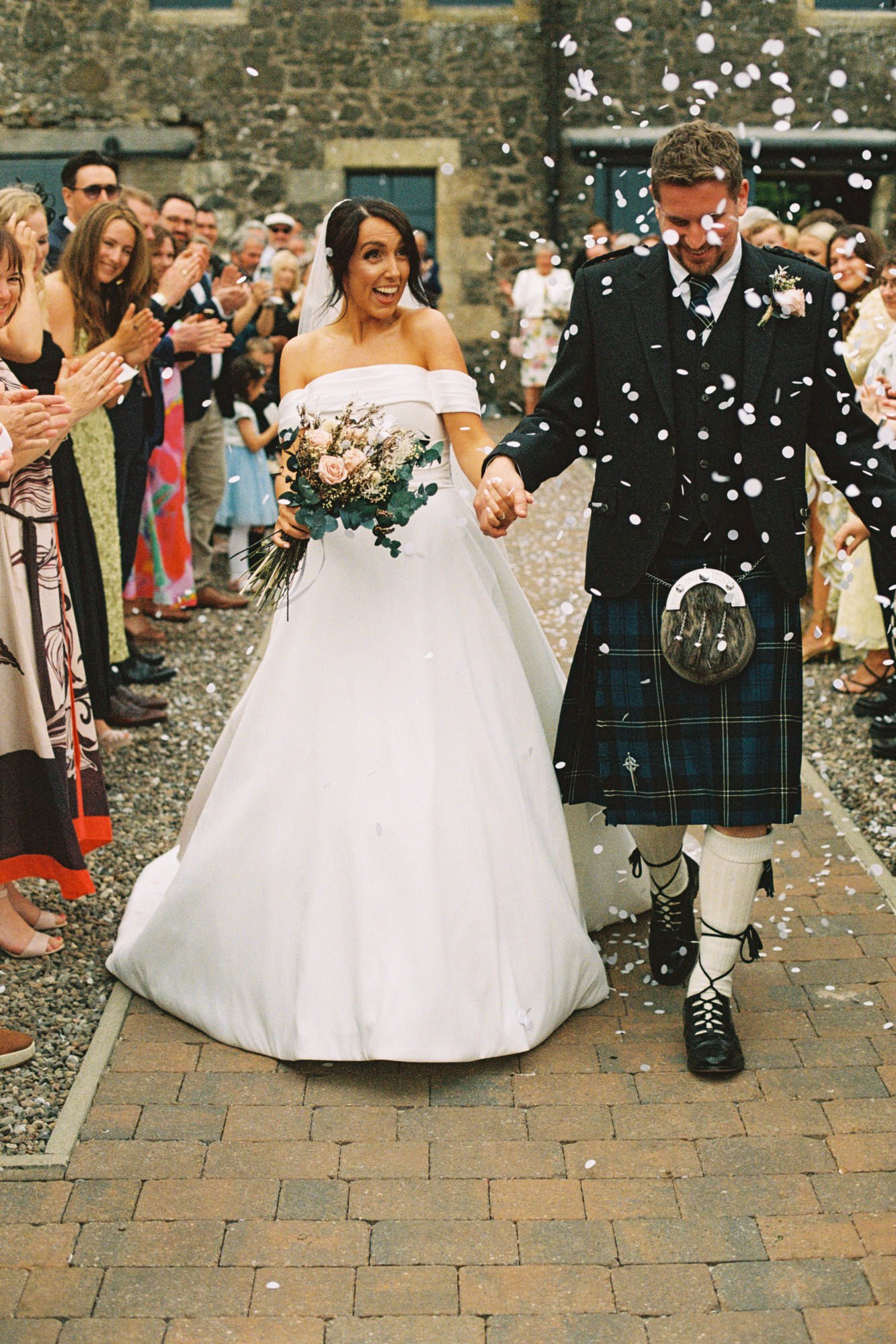 Newlyweds walking through a shower of confetti in Fife