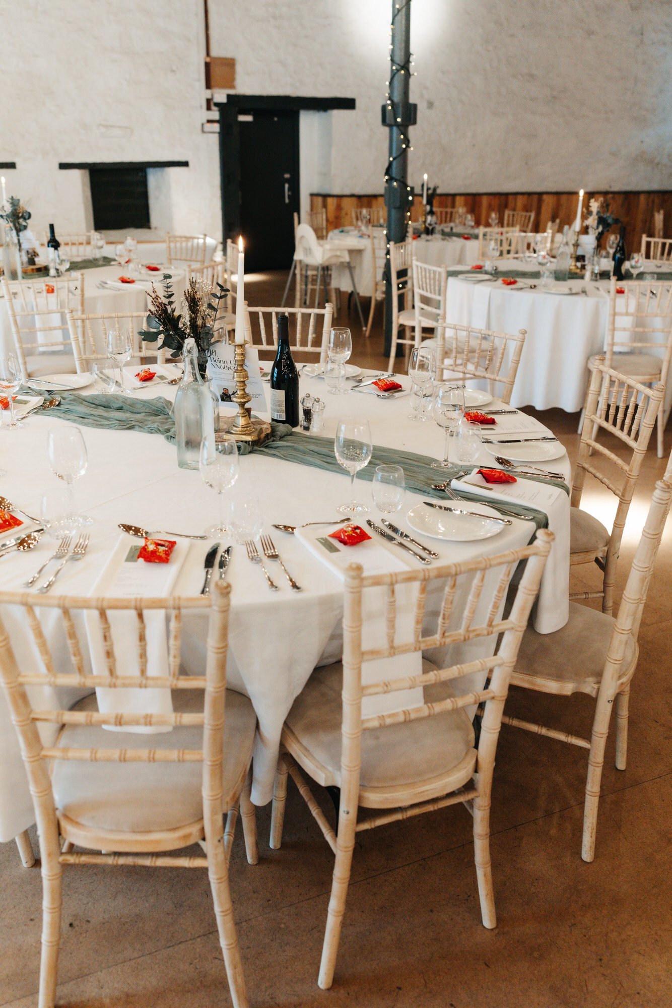 Wedding reception tables set beneath lights in the barn