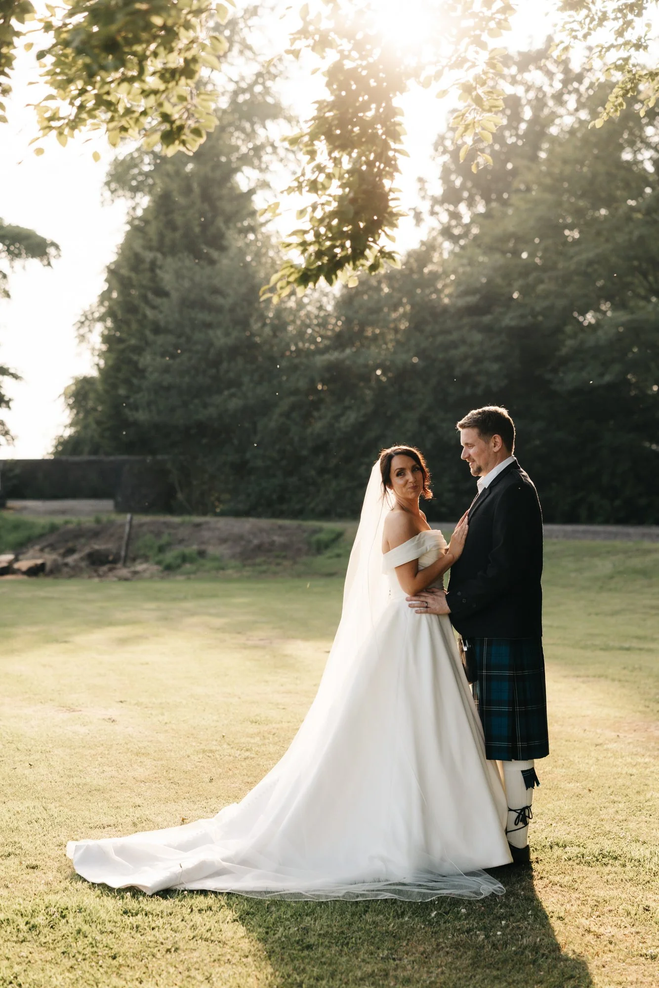 Claire and Alex standing beneath trees in the grounds