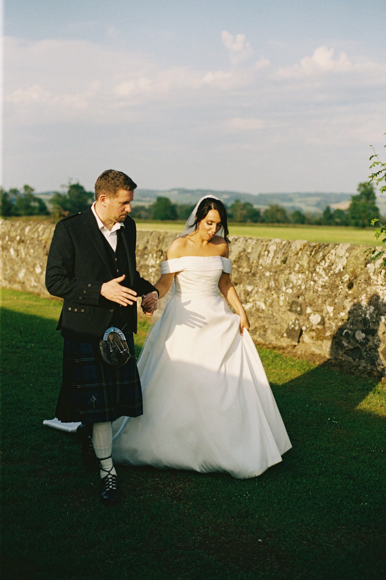 Couple walking beside a stone wall in the Fife countryside
