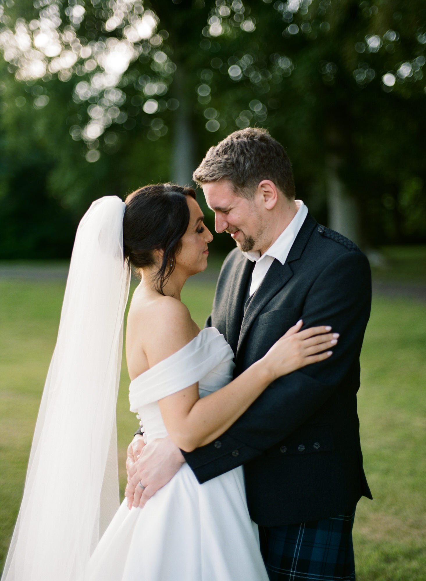 Claire and Alex looking at each other beneath the trees