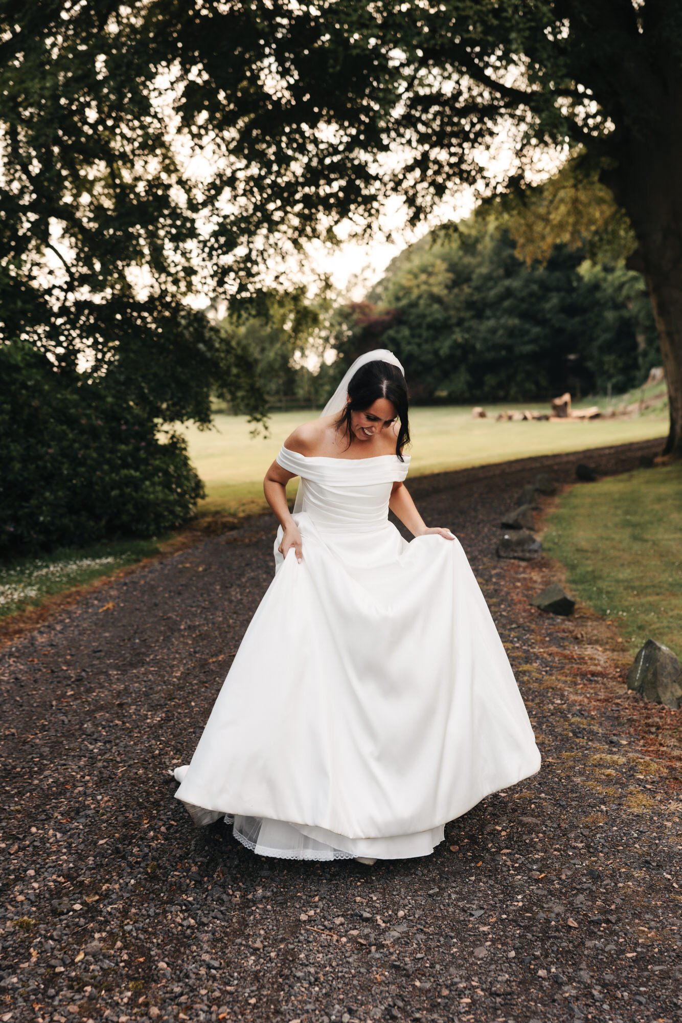 Claire walking along a gravel path in her wedding dress