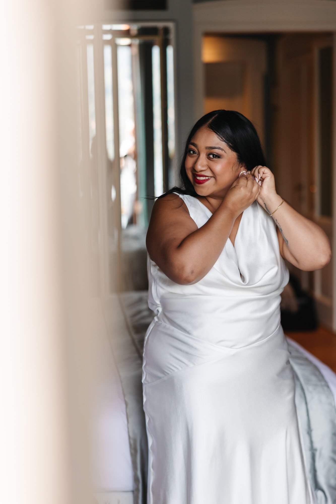 Velia adjusting her earrings in her wedding dress