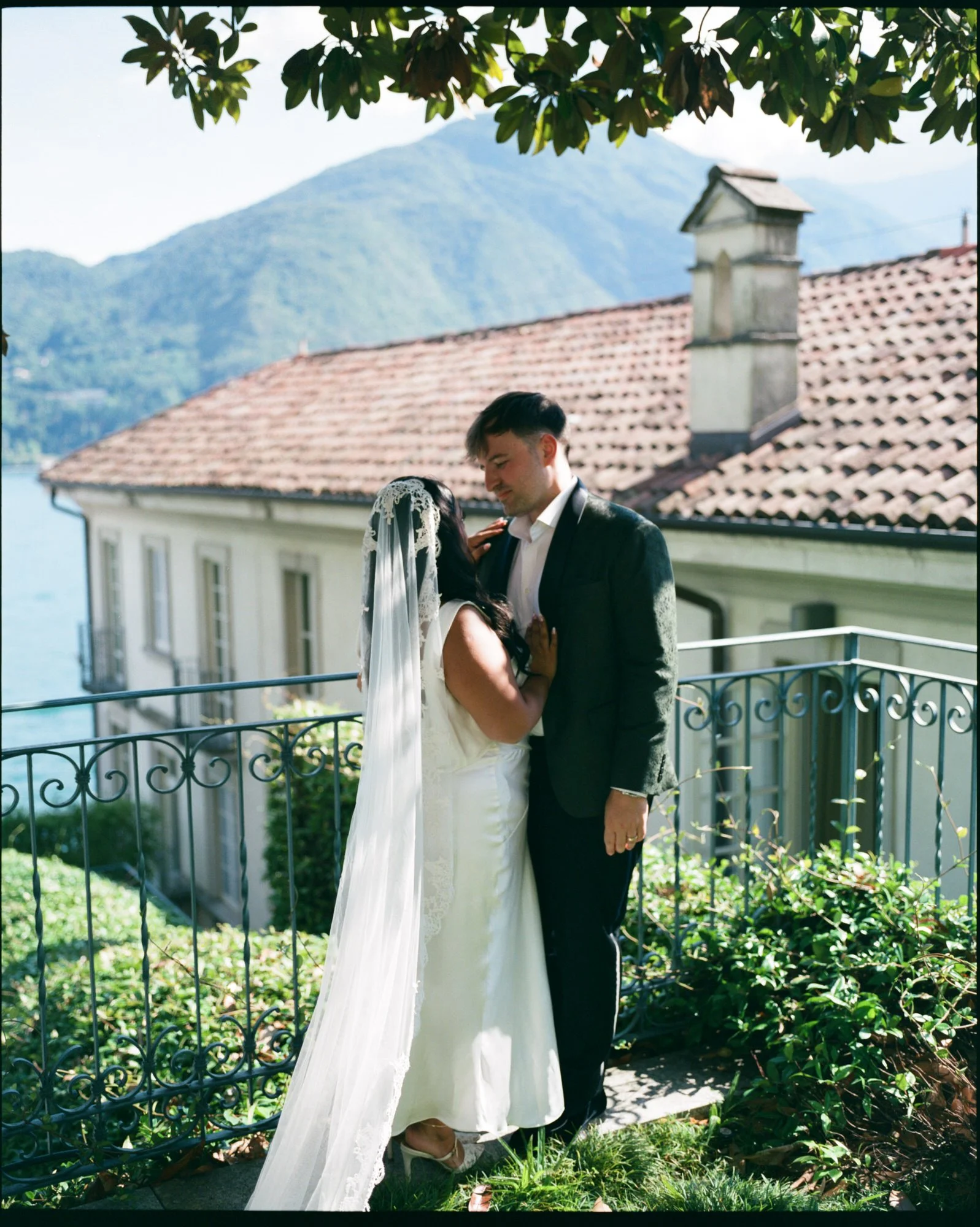 The couple sharing a kiss beside the garden railing
