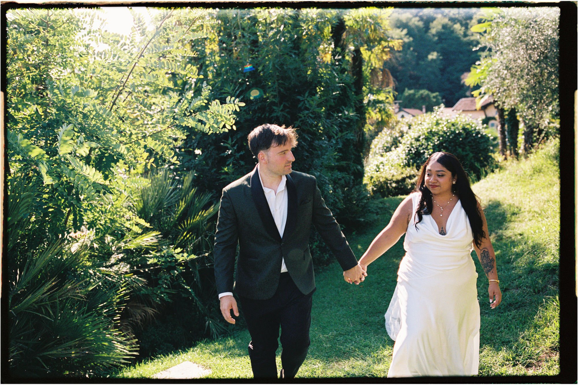 Velia and Dan walking hand in hand through the gardens