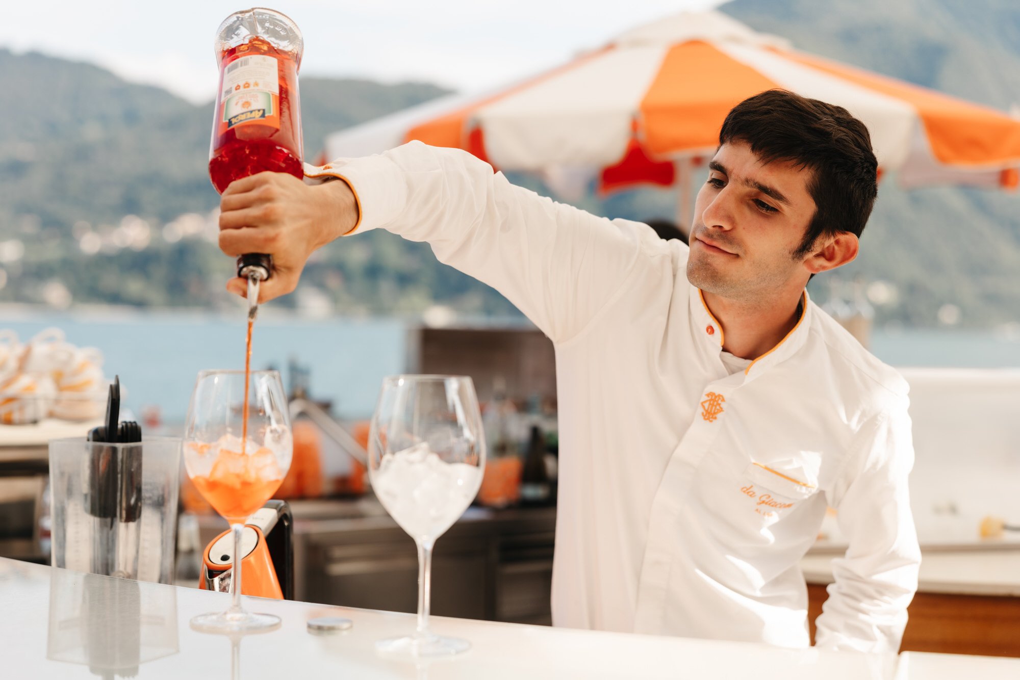 A bartender pouring a drink beside Lake Como