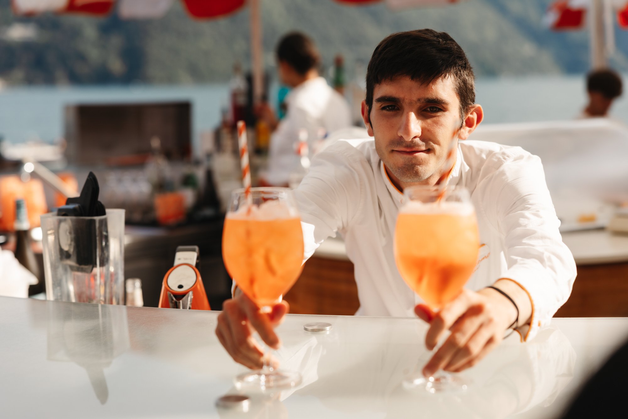 A bartender presenting two orange drinks