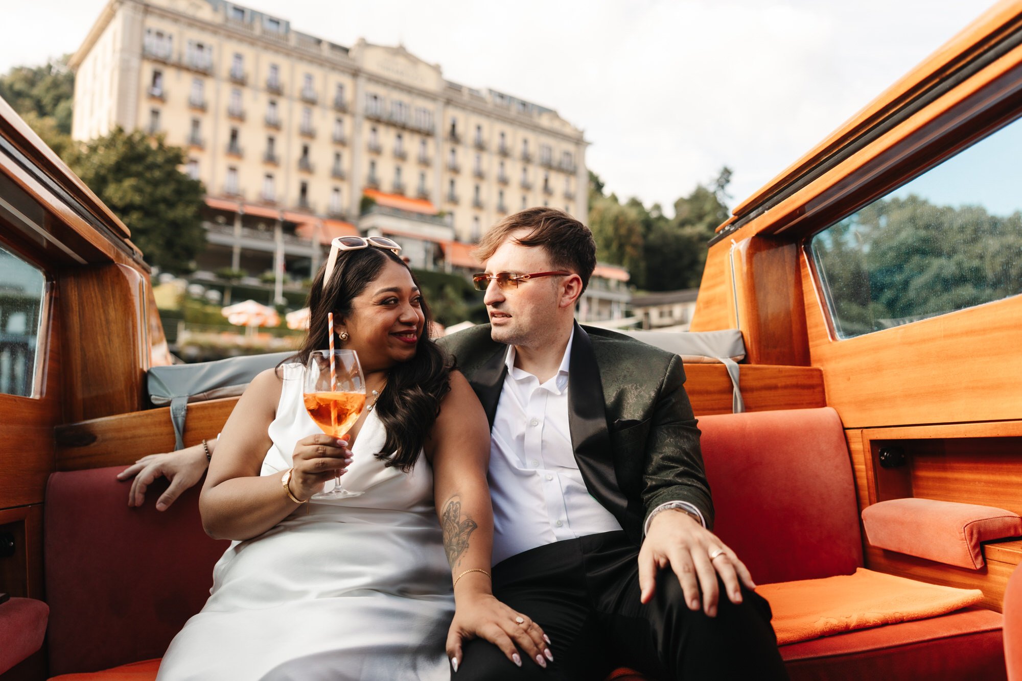 Velia and Dan seated on the boat with the hotel behind