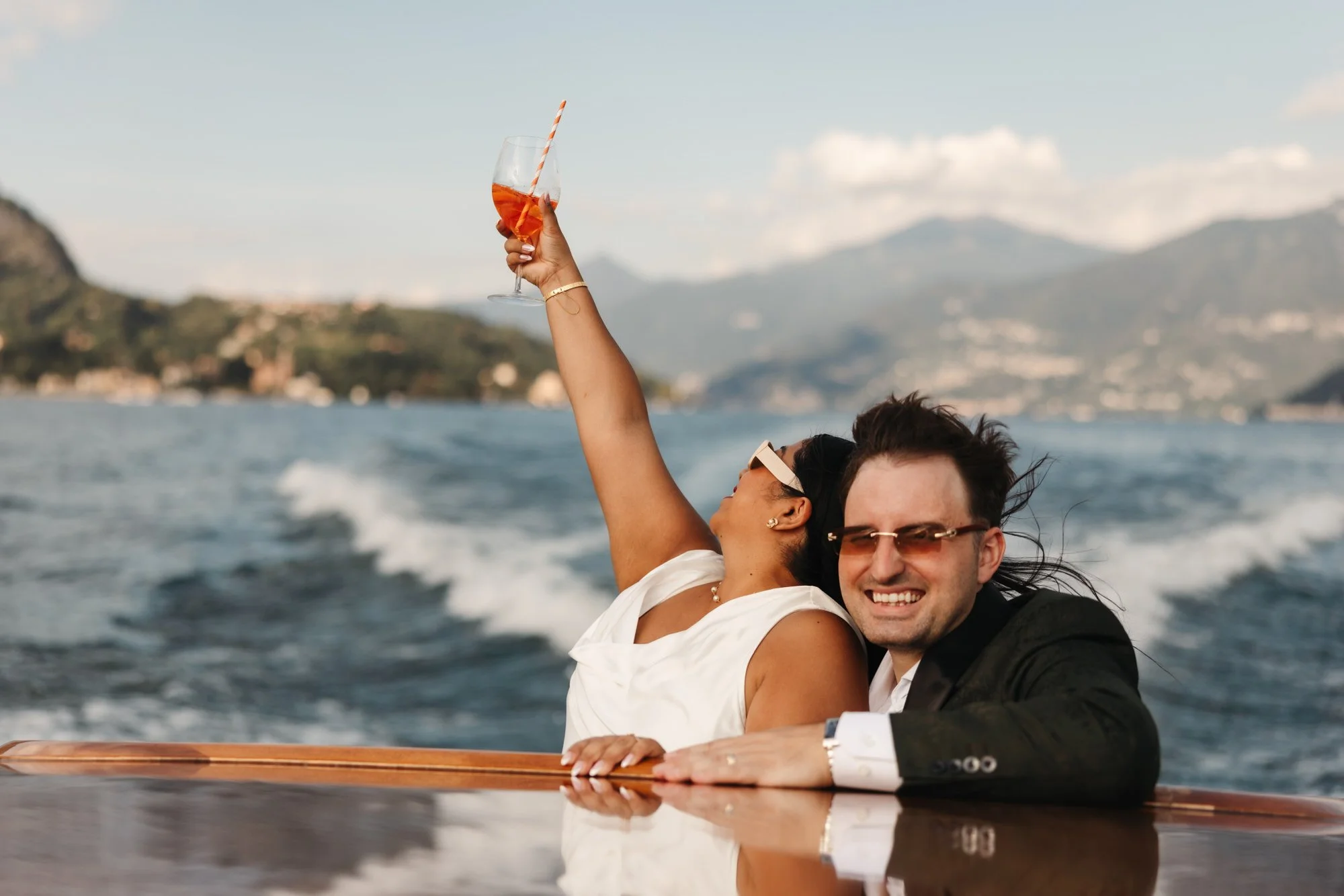 Velia raising her glass beside Dan on the lake