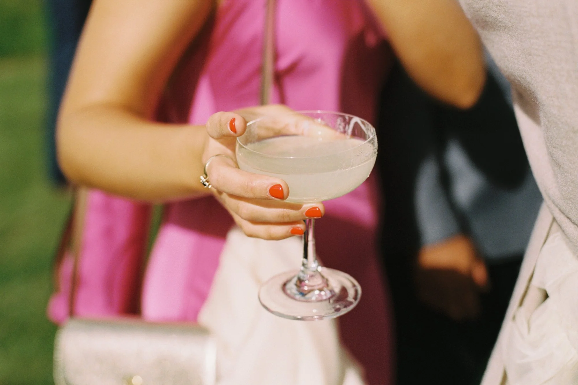 photograph  of wedding guest in pink dress holding a cocktail
