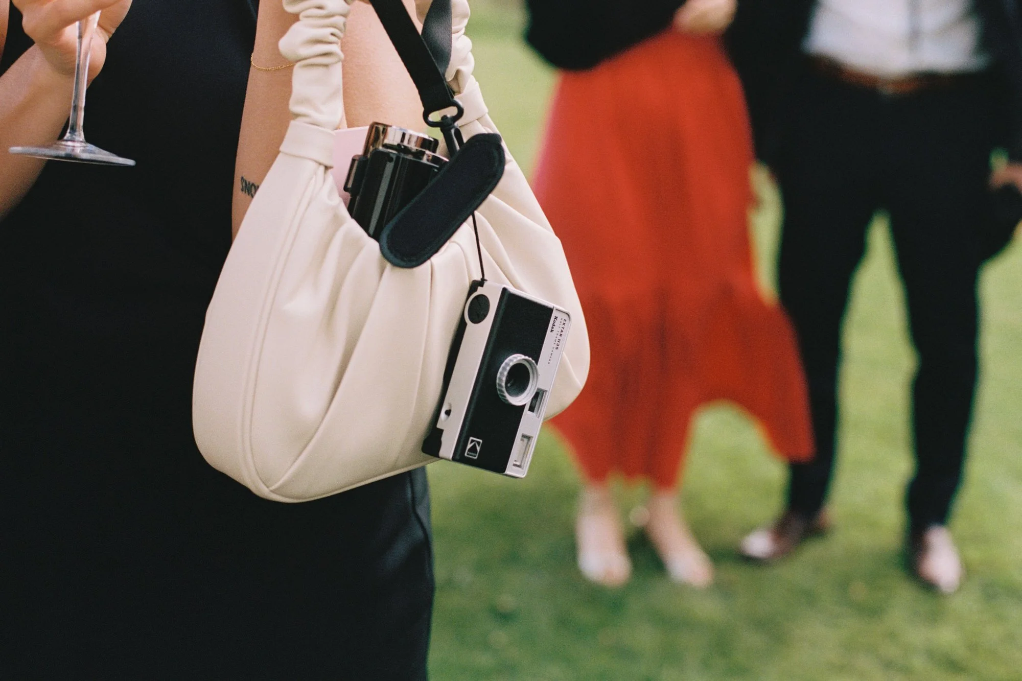 DETAILSHOT OF GUEST WITH FILM CAMERA AT A WEDDING