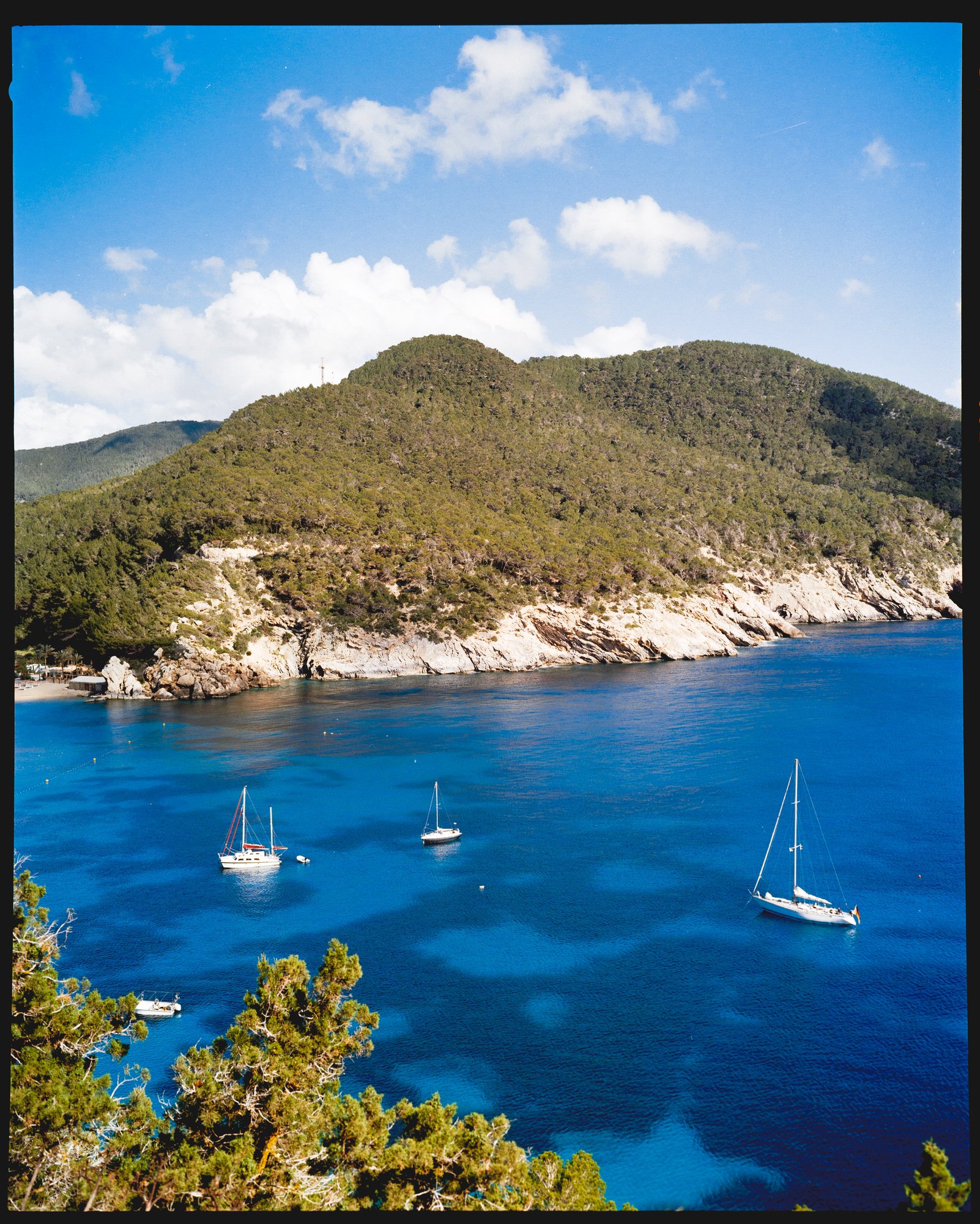 bright blue waters and a green hillside on coast of ibiza