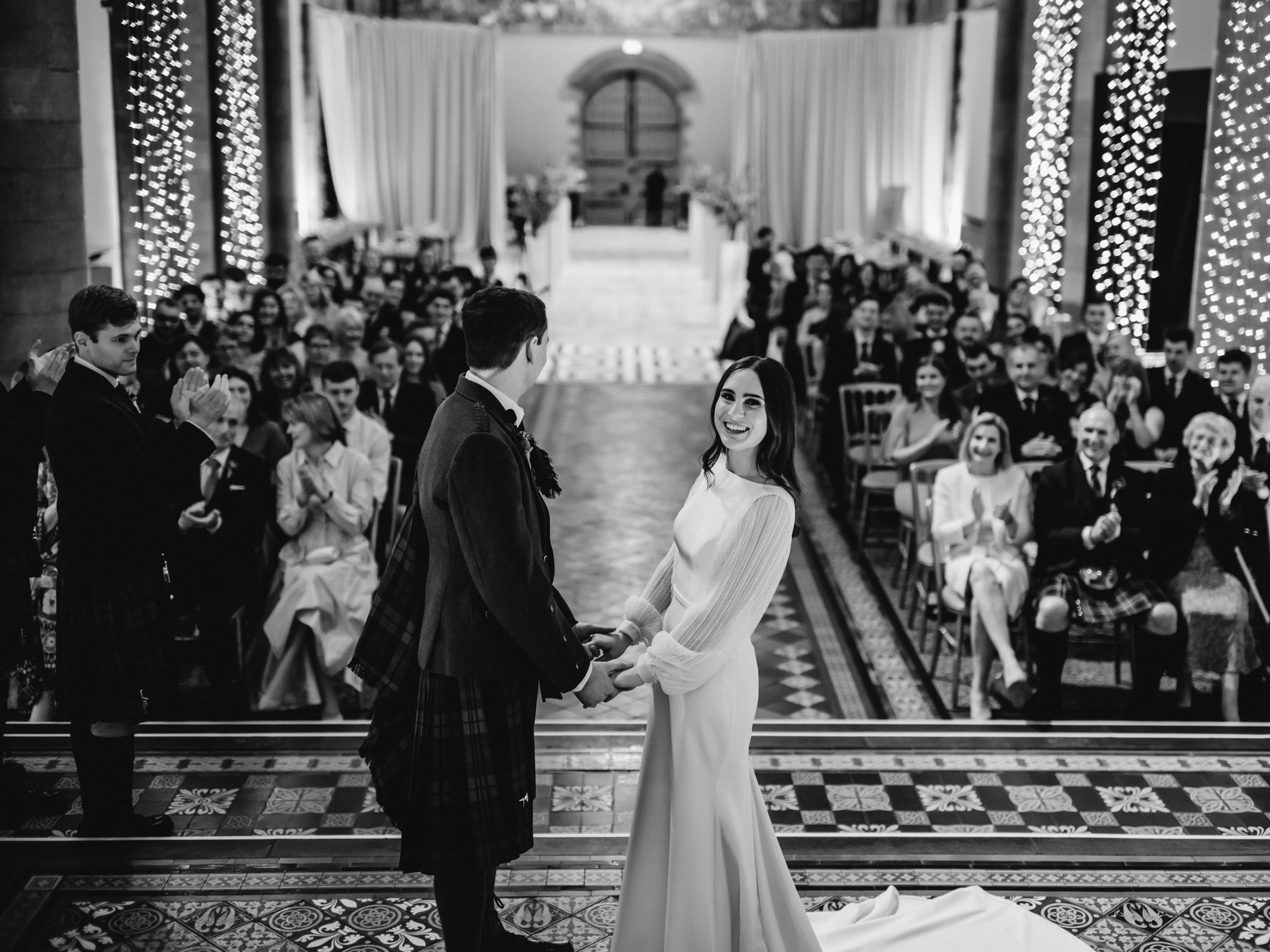 Black-and-white photograph of newlyweds surrounded by wedding guests