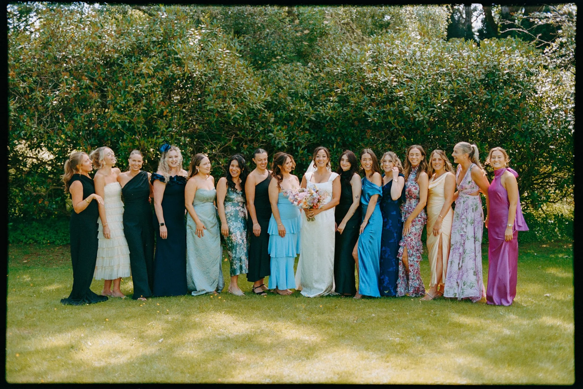 bride poses for photograph with her friends in colourful dresses