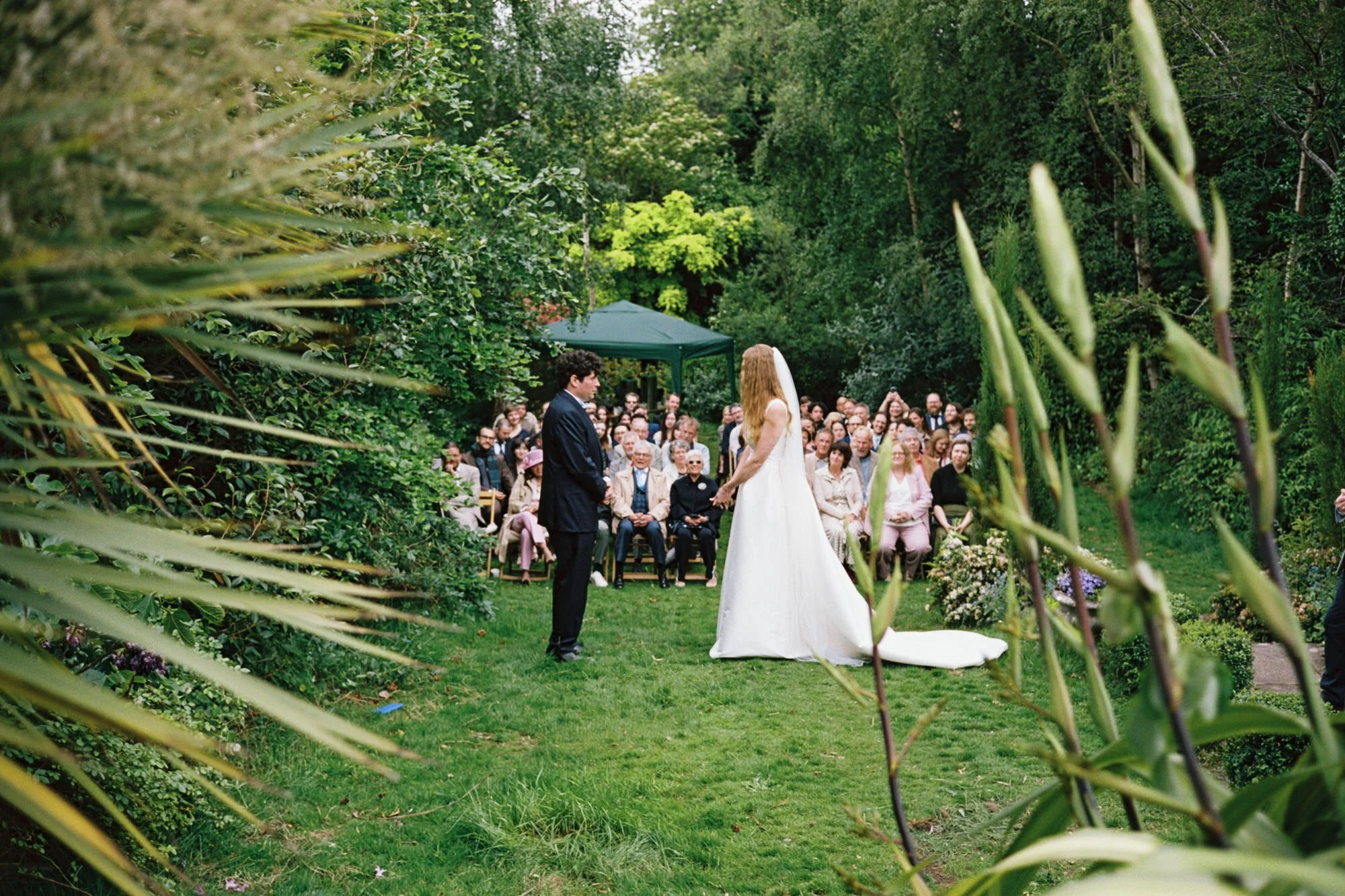 Newlyweds walking towards their outdoor garden wedding ceremony