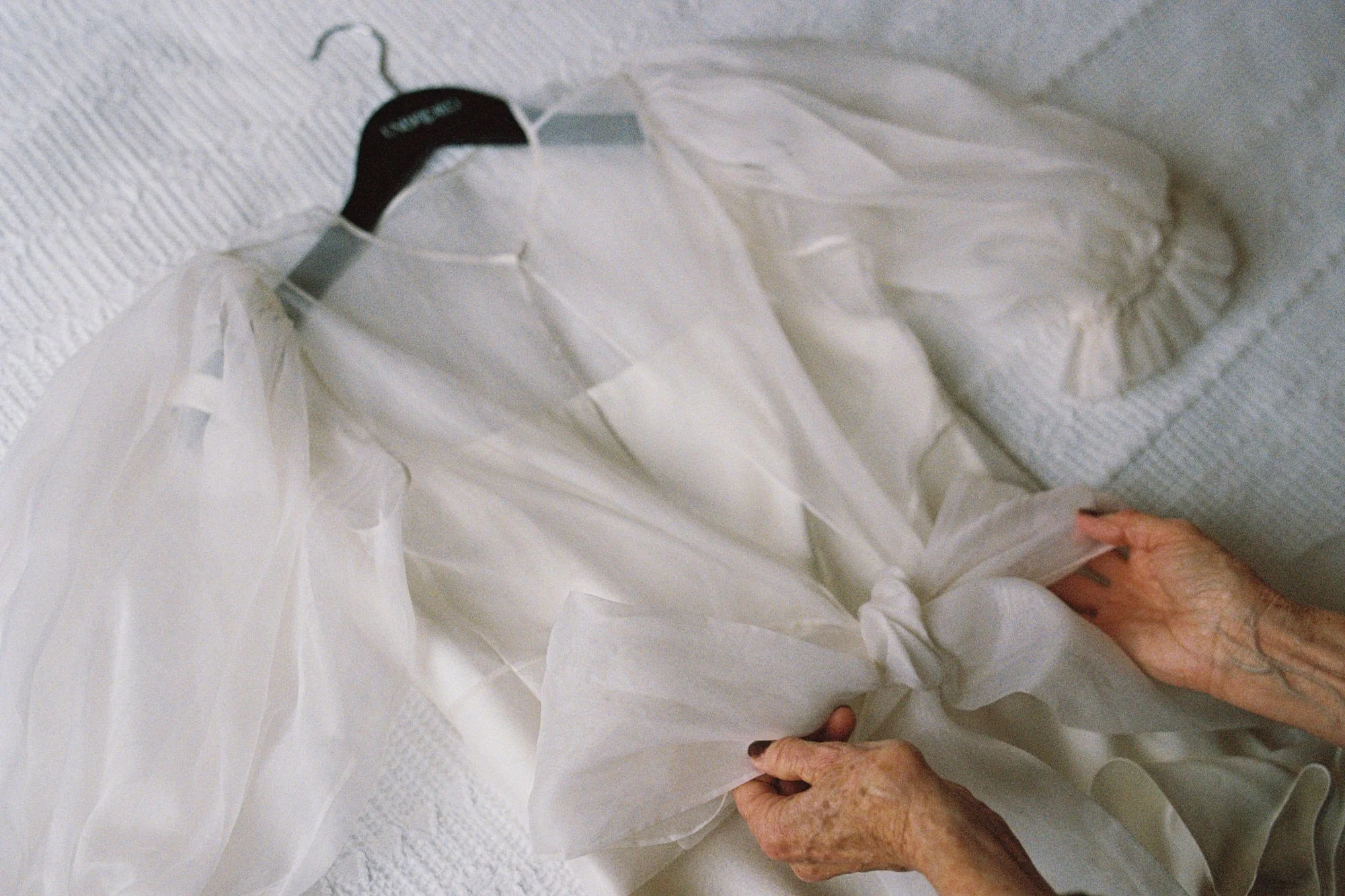 detail of mother of the bride timing bow on brides dress before she puts its on