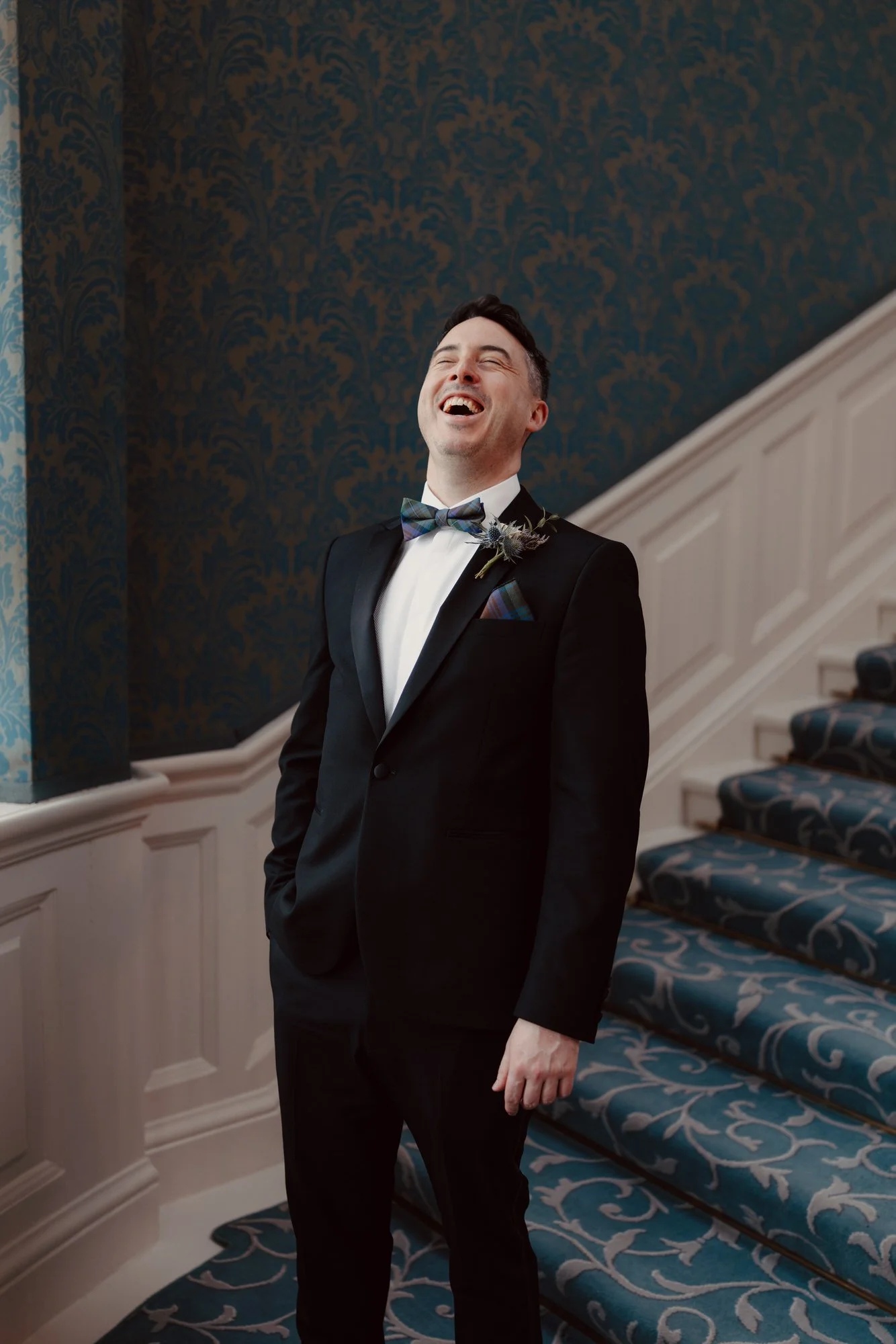 portrait of a groom in black tie laughing