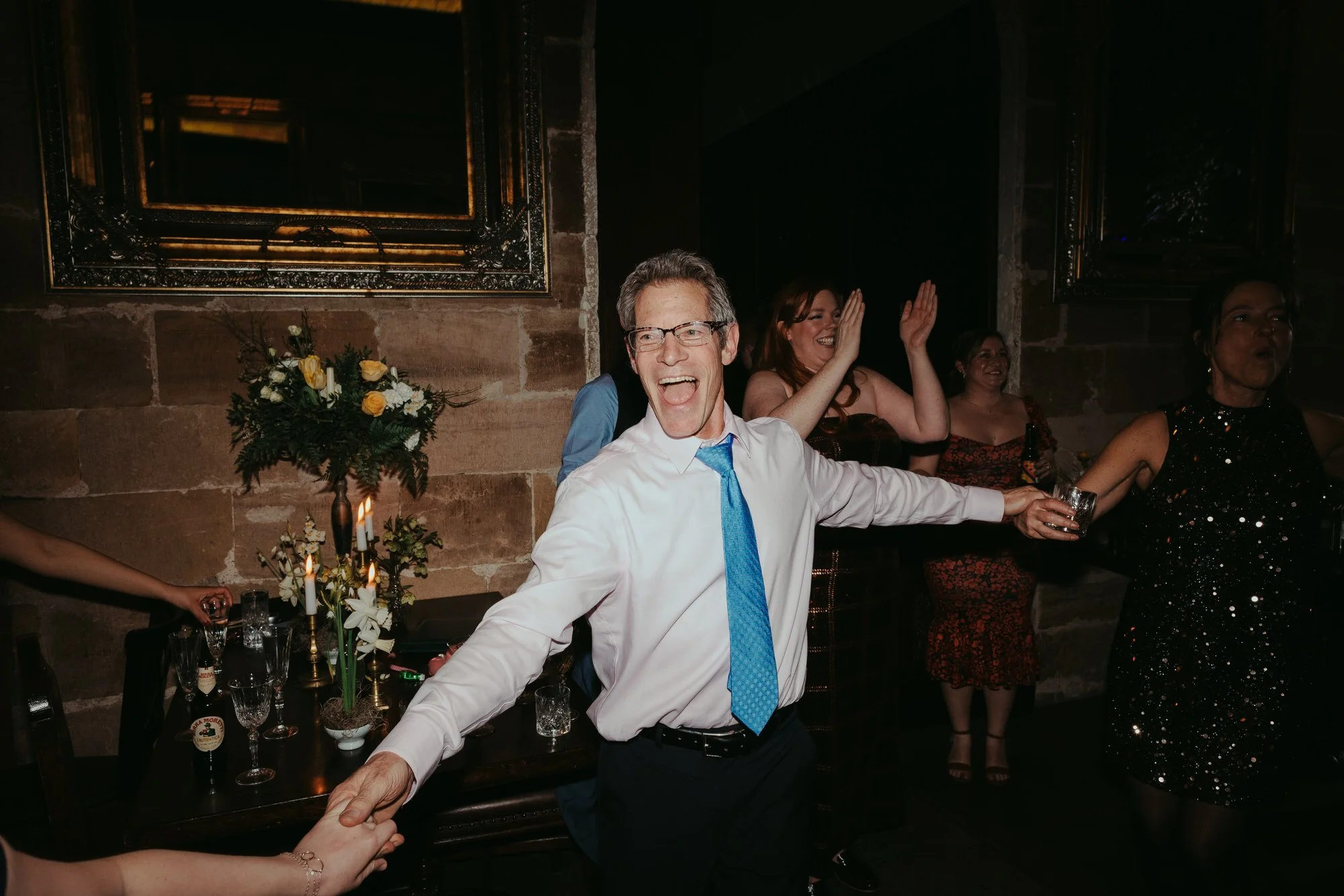 guest at wedding dancing while holding hands with people out of shot