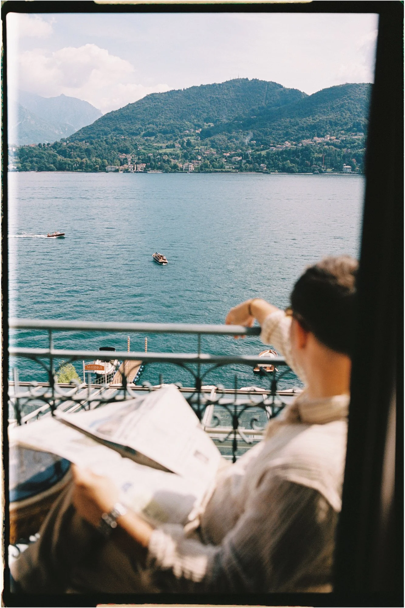 Groom looks out towards boats on the balcony of hotel grand trezzimo