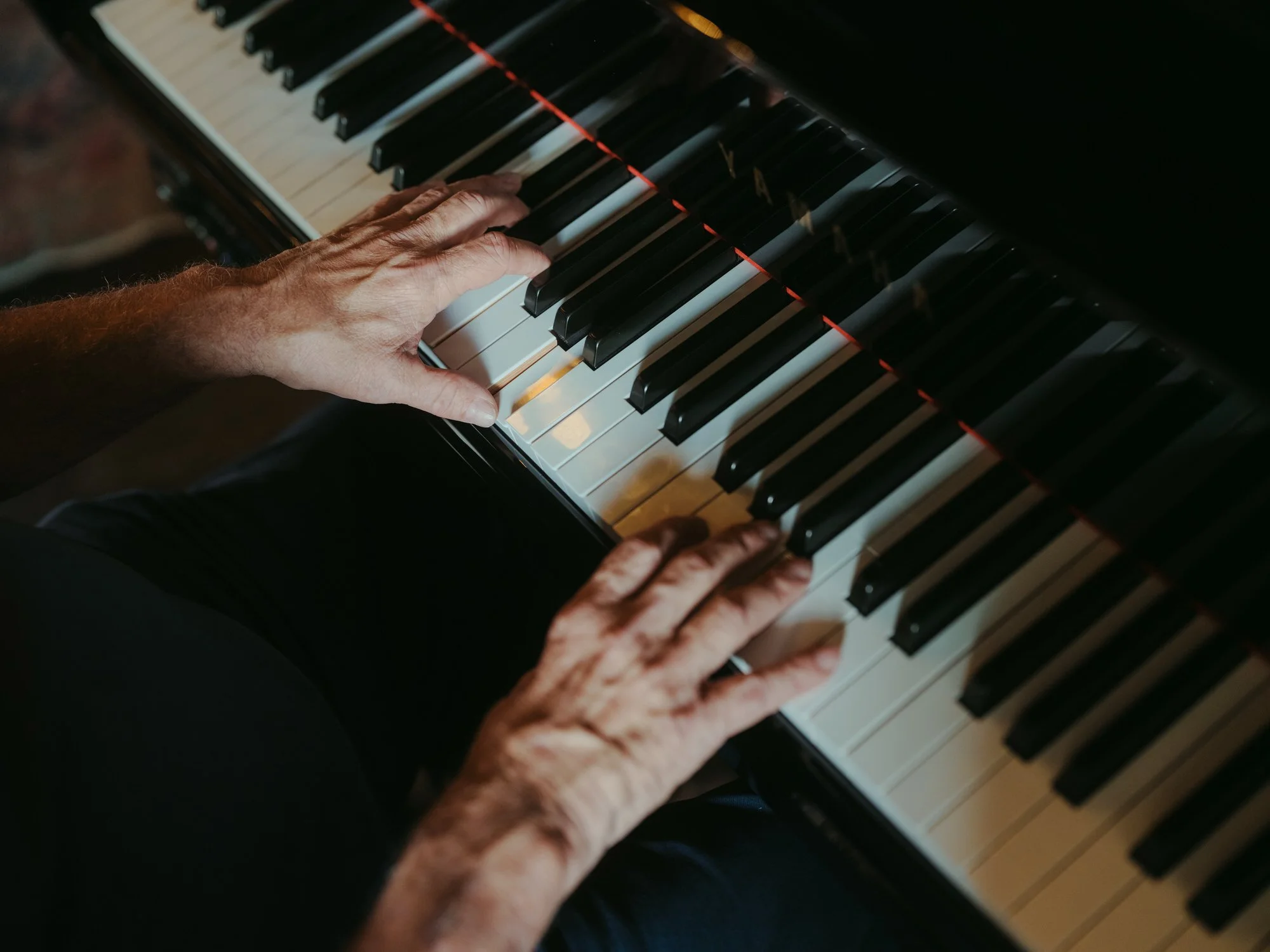 Close-up of person's hands playing a grand piano keyboard, seen from above. Photographed by Steven William Weir, Edinburgh Scotland.
