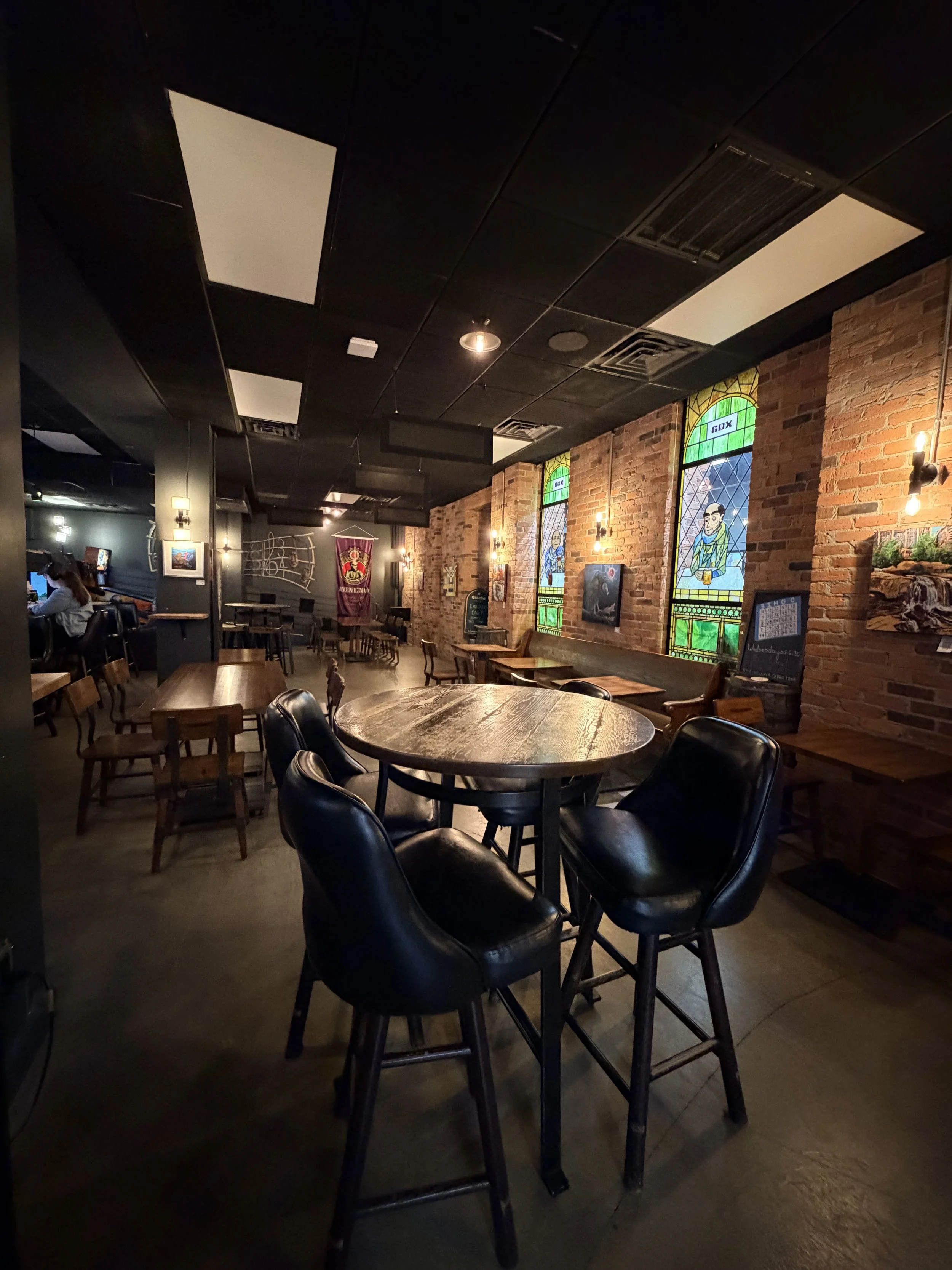 "A wide view of the inviting taproom at Greenville Beer Exchange. The layout features a mix of high-top bar tables and accessible low-top seating