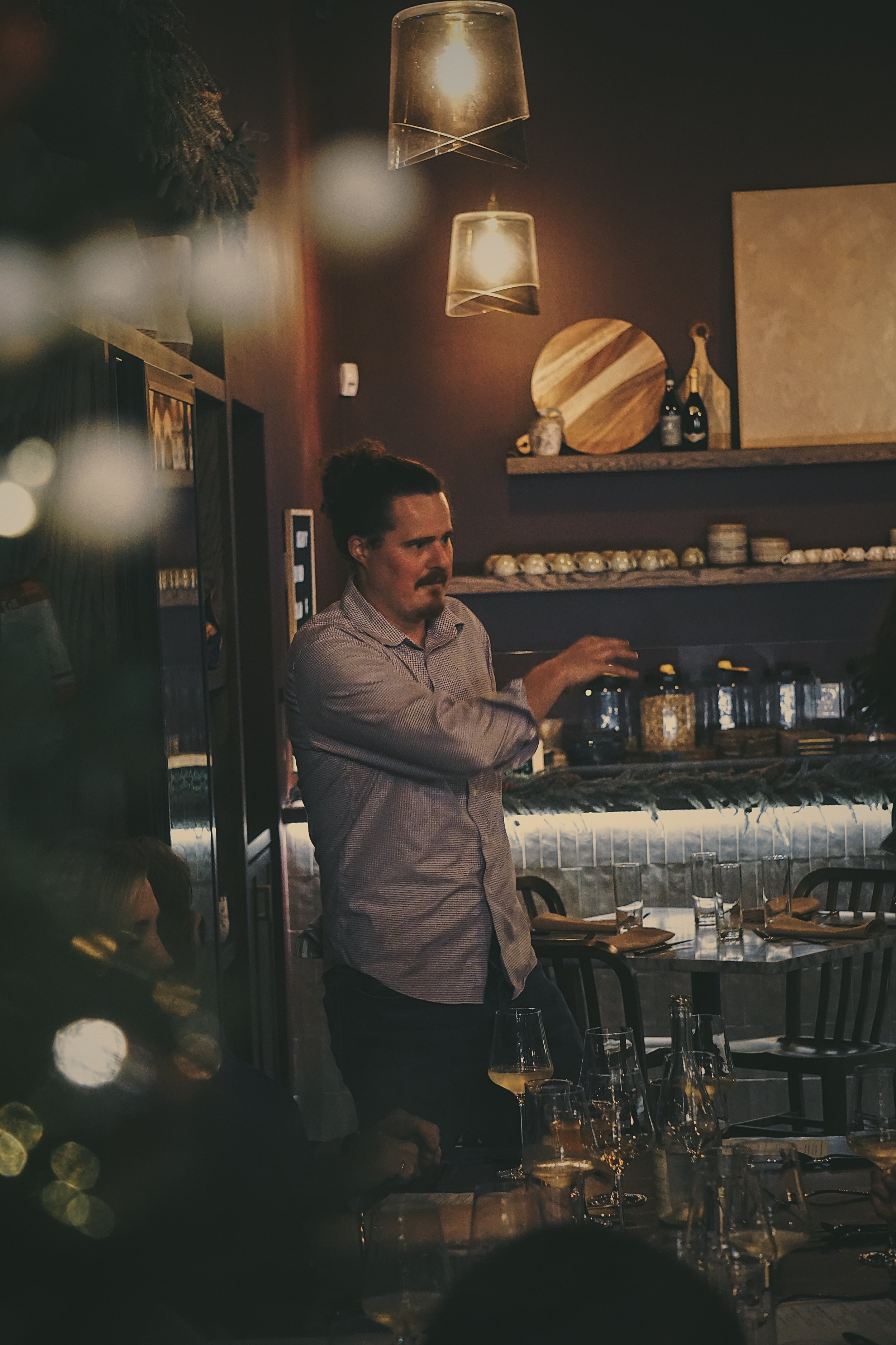 Kevin P,  Sommelier and partner in Amy’s hospitality network, stands and addresses guests at a private wine dinner.