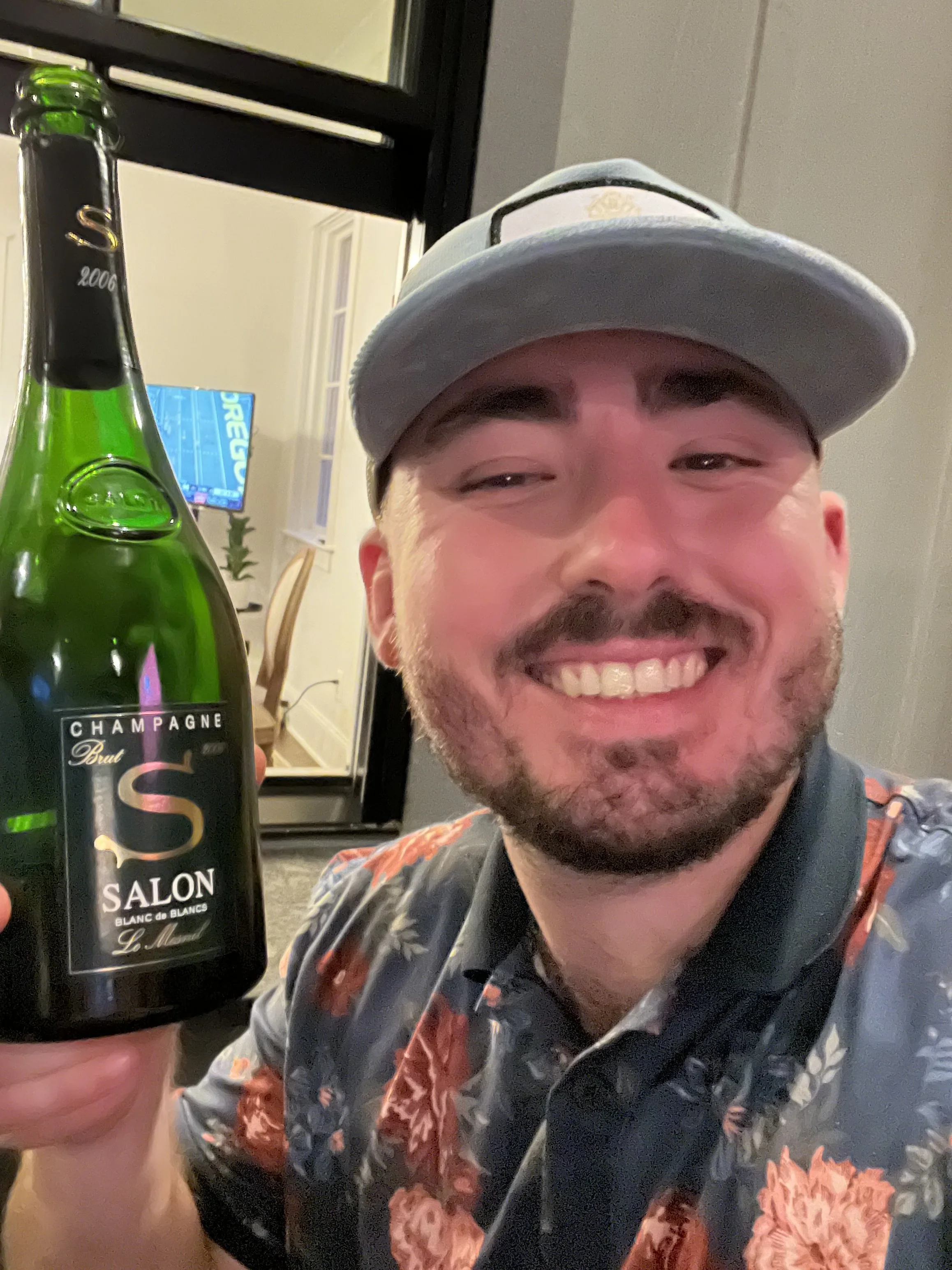 Sommelier Travis G. smiling broadly while presenting a rare bottle of Salon Champagne to the camera