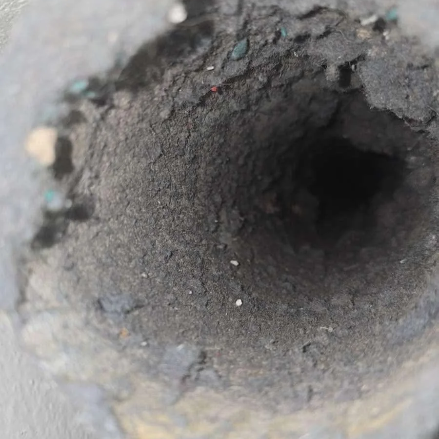 Close-up of a dirt-filled hole or pipe opening in the ground.