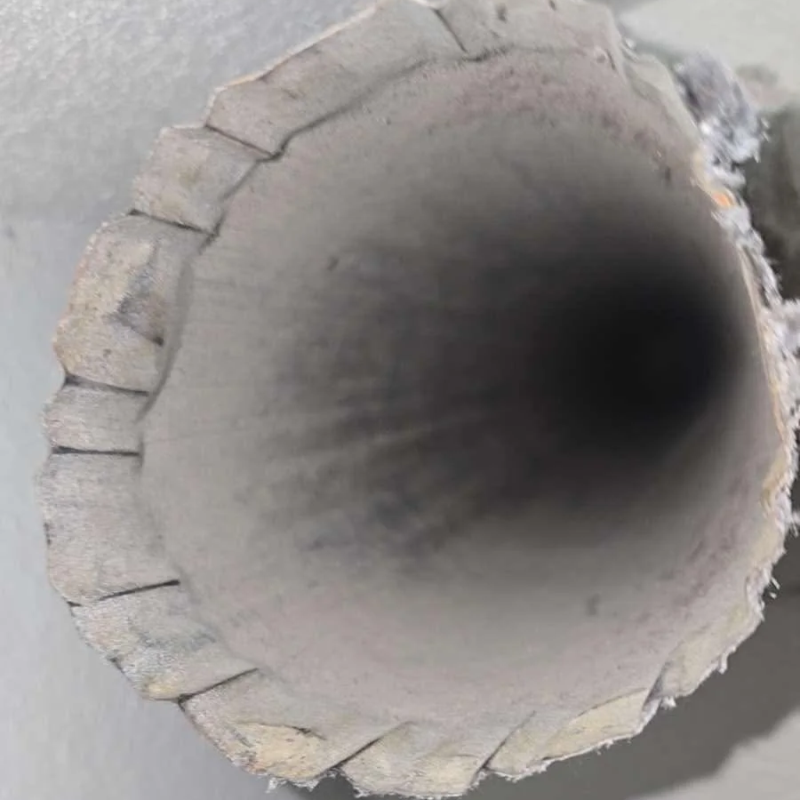 Close-up of the end of a metallic tube with a notched or ridged edge.