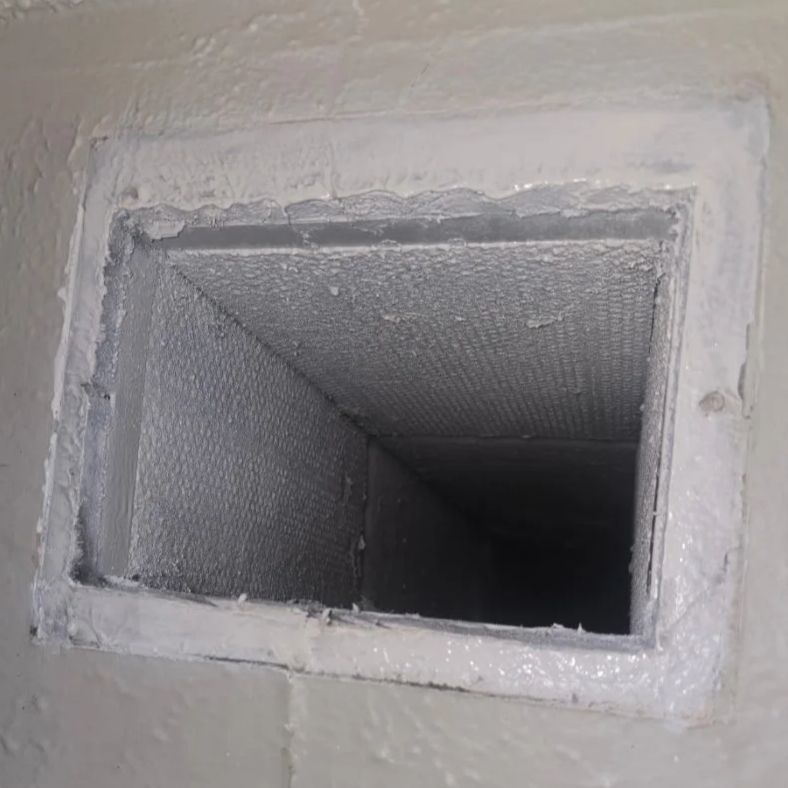 Close-up of an air vent or duct opening with a metal screen, surrounded by painted drywall.