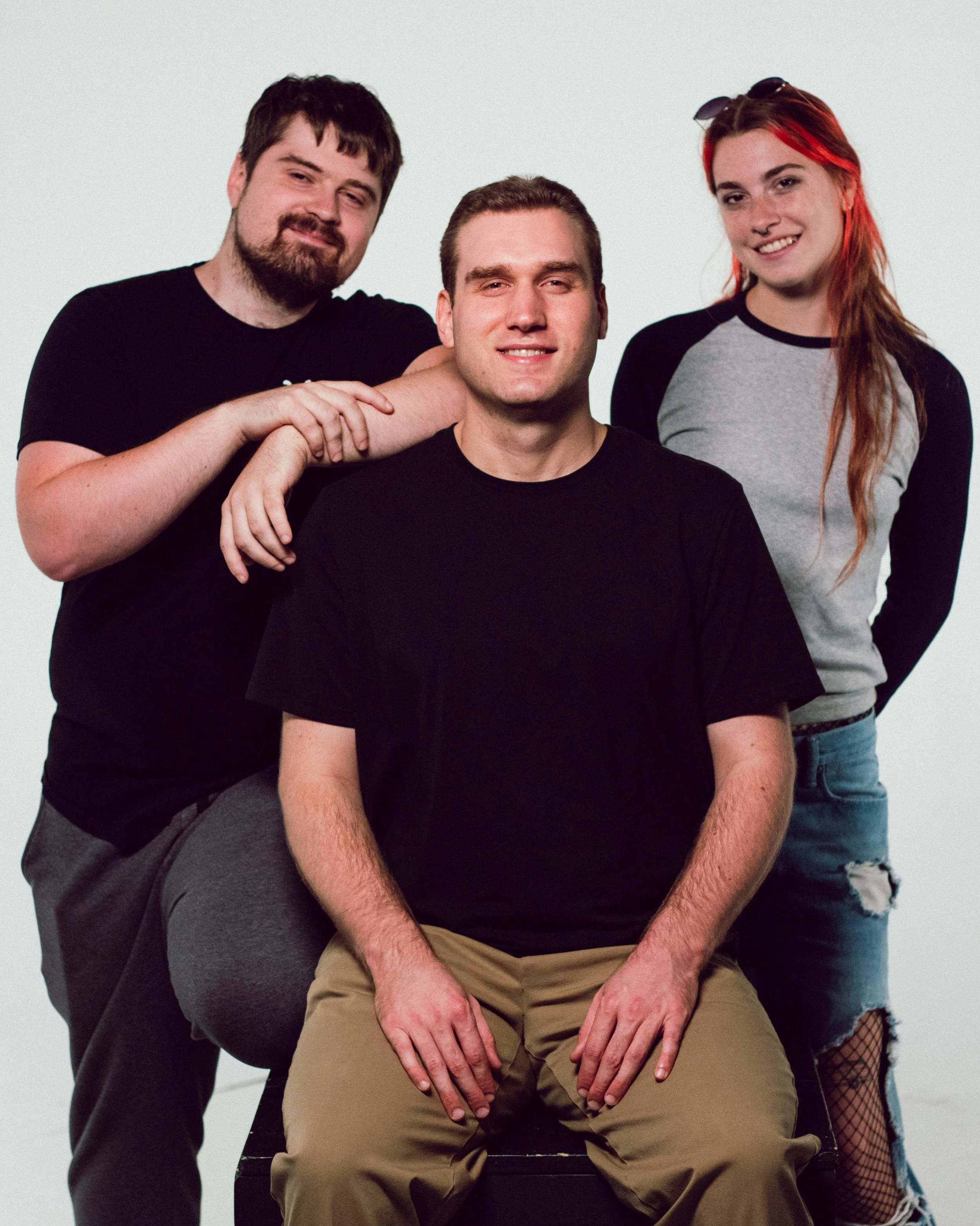 A group of three men and one woman posing against a plain background.