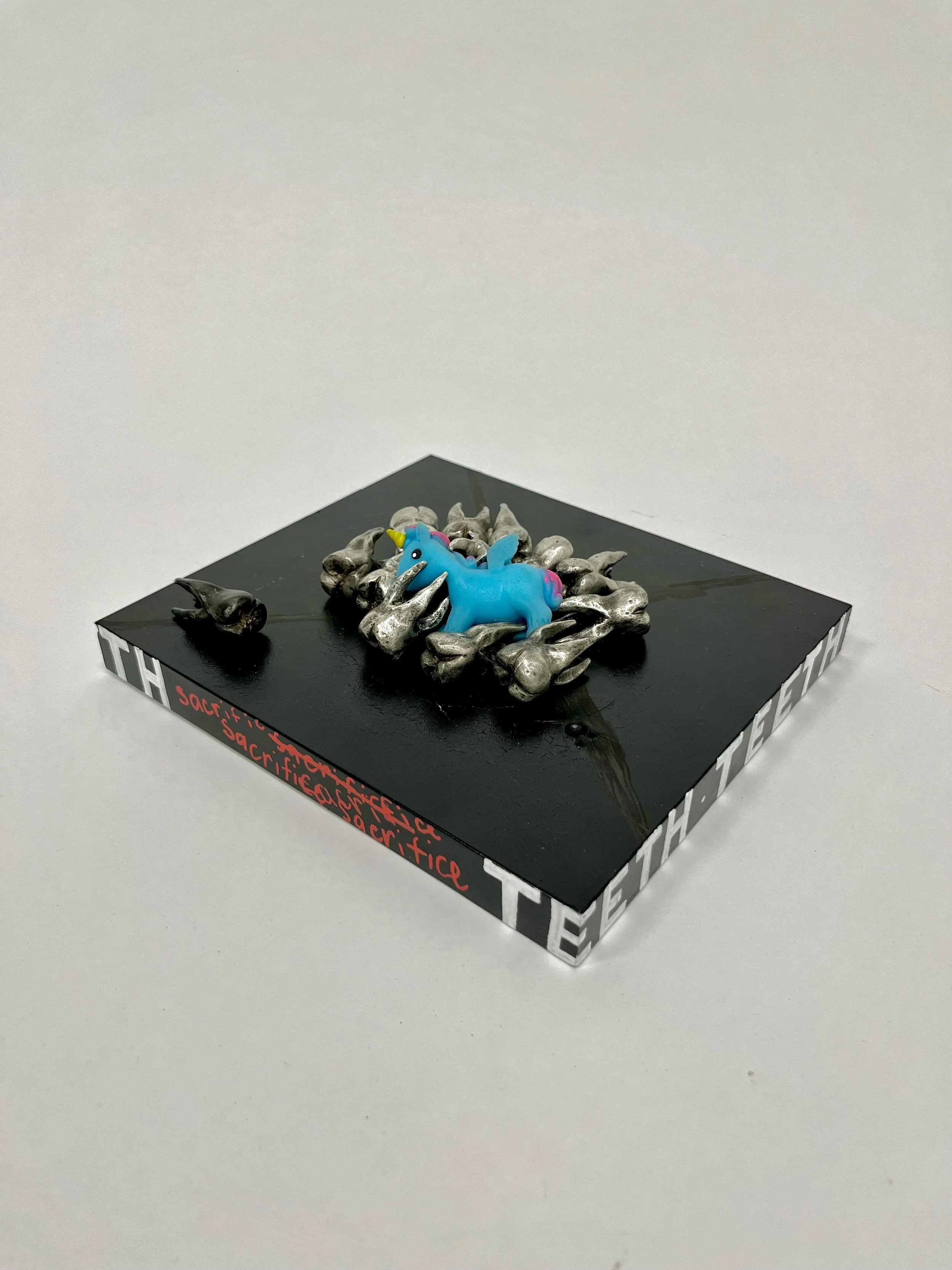"TEEEEEEETH"
Individual Tooth: 1” x 1.5”
Presentation: 8.5” x 9.5” x 2.5”, 
Pewter cast tooth, found unicorn toy, wood, spray paint, 
2025