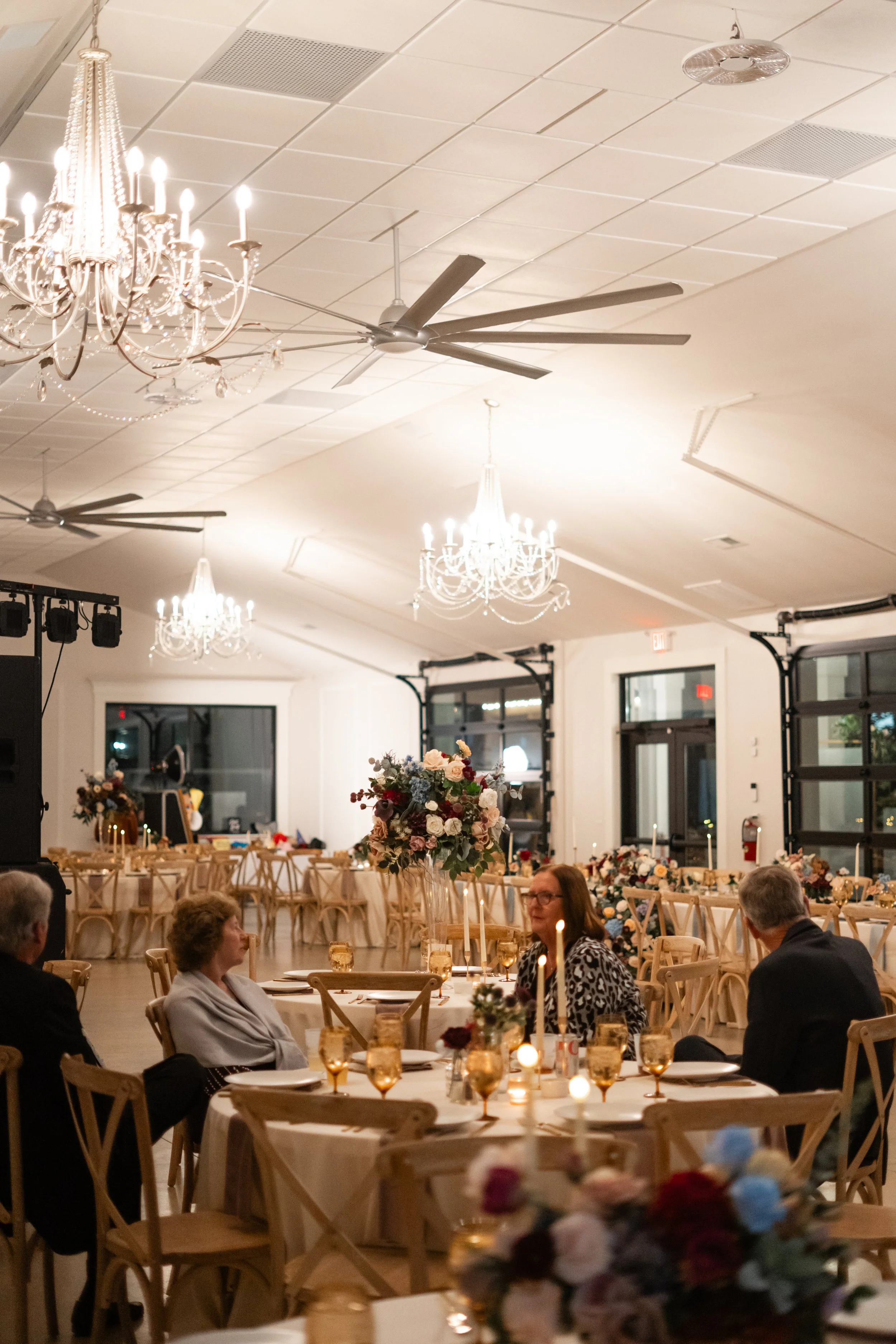Elegant banquet hall decorated with chandeliers, floral centerpieces, and candlelit tables for a formal event.