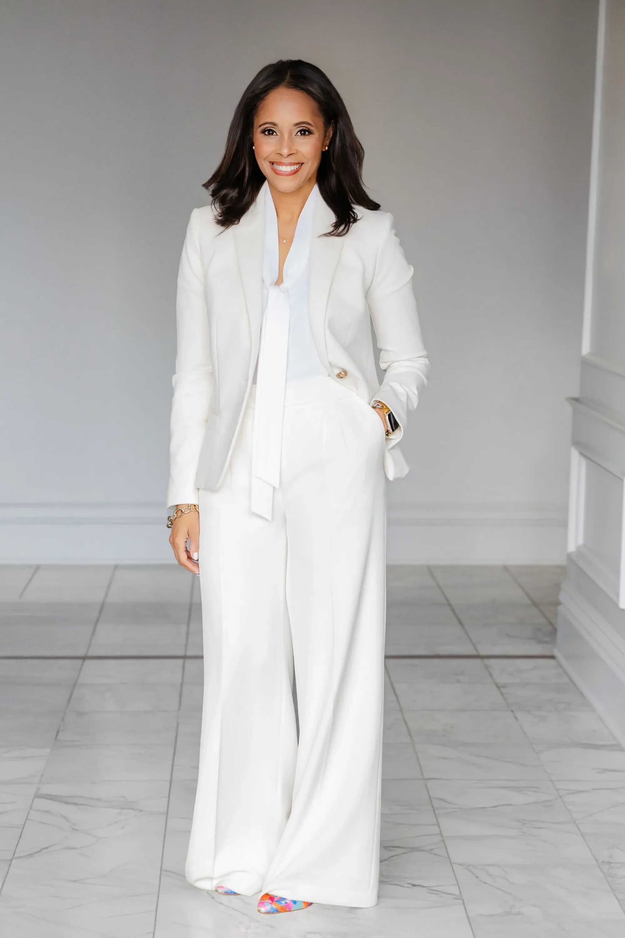 Melanie R. Bridgeforth, MSW, founder of Bridgeforth, portrait in a white suit against a gray backdrop